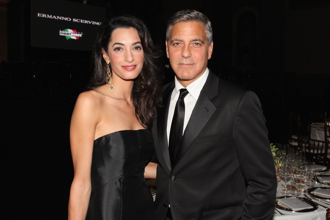 Amal Clooney and George Clooney pose for photos at an event
