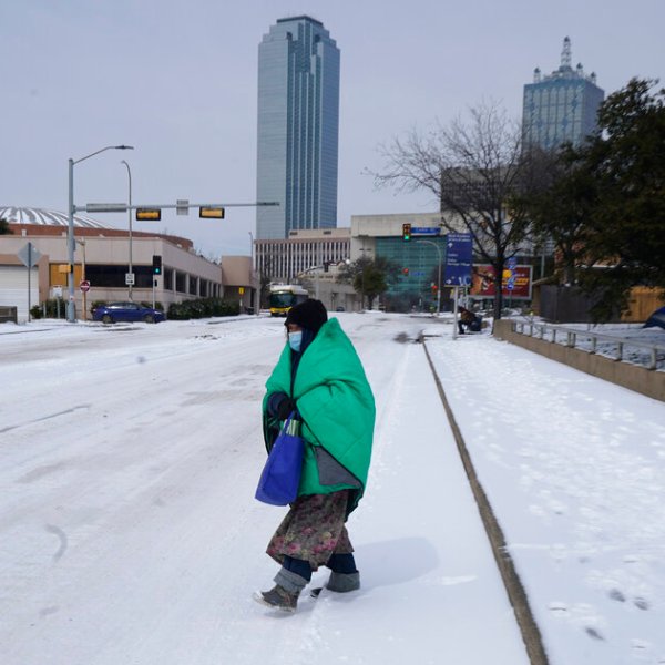 a woman wrapped in a blanket crosses the street