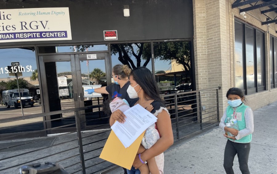 A migrant woman carrying a baby and DHS-issued release papers is led to the Humanitarian Respite Center in downtown McAllen, Texas.