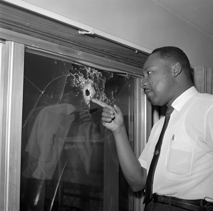 Martin Luther King. Jr. looking at a bullet hole in a glass window
