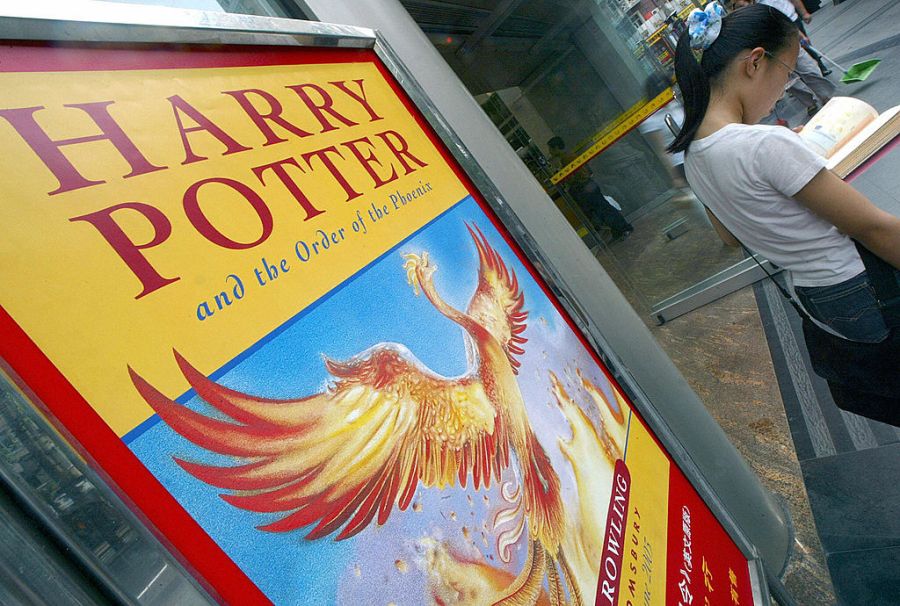 A girl reads a book next to a poster promoting the fifth Harry Potter book