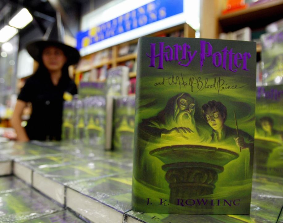 A sales woman stands next to copies of 'Harry Potter and the Half-Blood Prince'