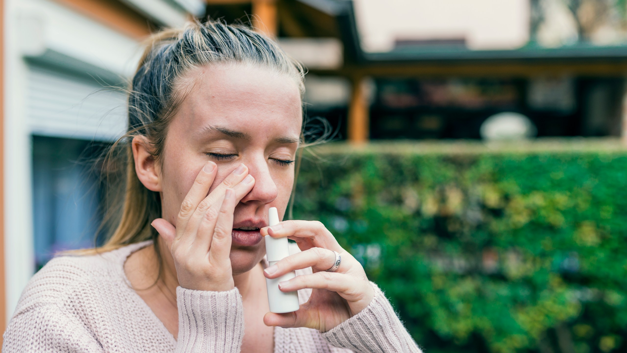 Sick woman using nasal spray