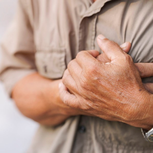 Close-up of an elderly man's hand held his chest in pain