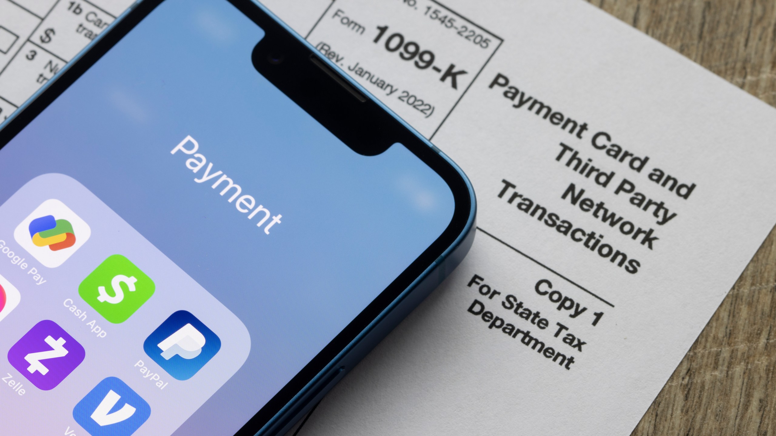 Payment apps like PayPal and Venmo are seen on an iPhone on top of a tax form.