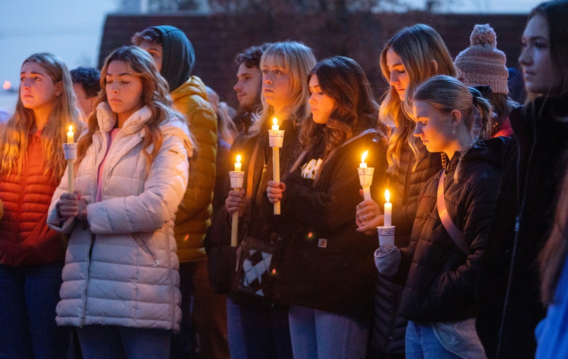 People pay their respects at a vigil held in front of a statue on the Boise State campus in 2022.