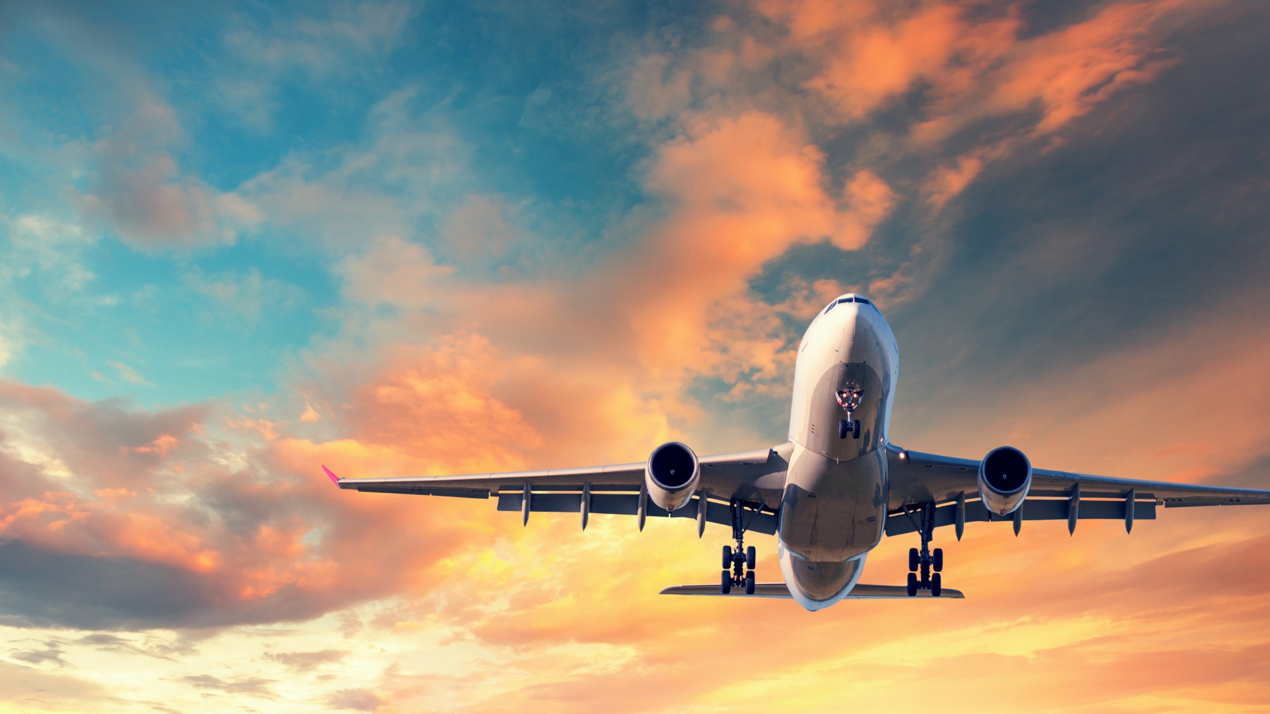 Landing airplane. Landscape with white passenger airplane is flying in the blue sky with multicolored clouds at sunset. Travel background. Passenger airliner. Business trip. Commercial aircraft - stock photo