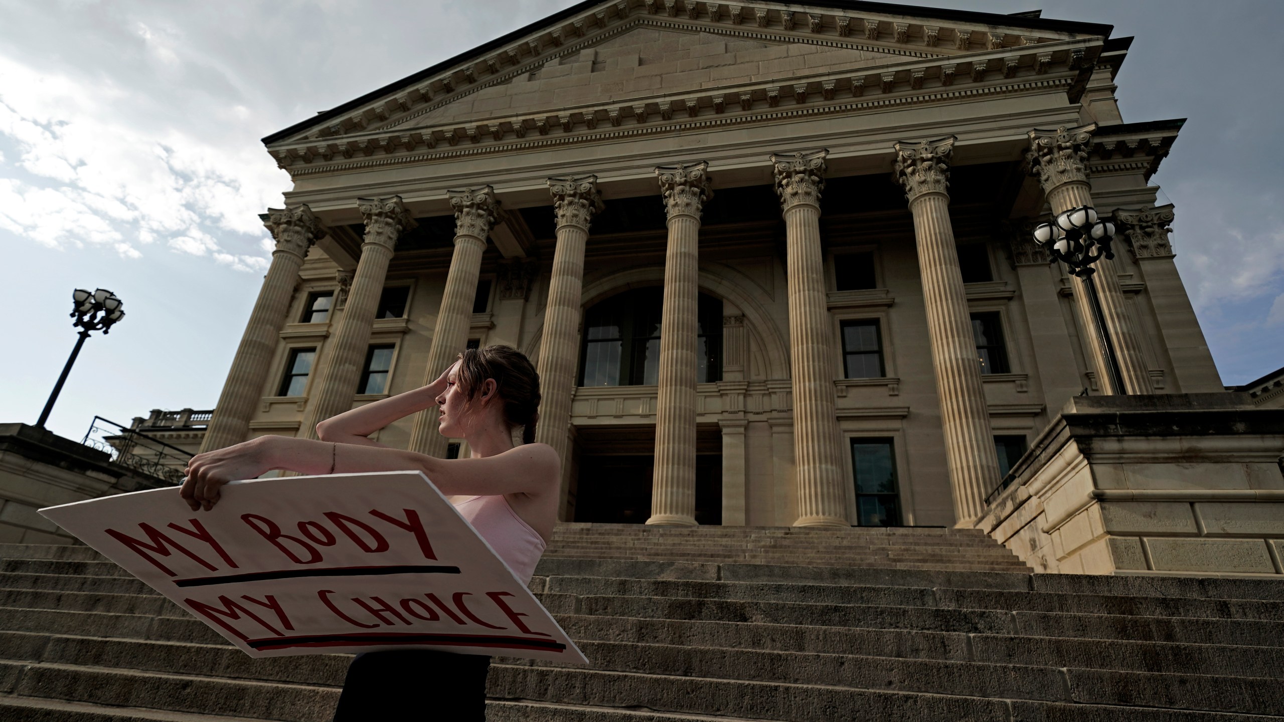 FILE - Zoe Schell, from Topeka, Kan., stands on the steps of the Kansas Statehouse during a rally to protest the Supreme Court's ruling on abortion, June 24, 2022, in Topeka. Abortion providers sued Kansas on Tuesday, June 6, 2023, challenging a new law requiring them to tell patients that an abortion medication can be stopped but also existing restrictions that include a decades-old requirement that patients wait 24 hours to terminate their pregnancies. (AP Photo/Charlie Riedel, File)