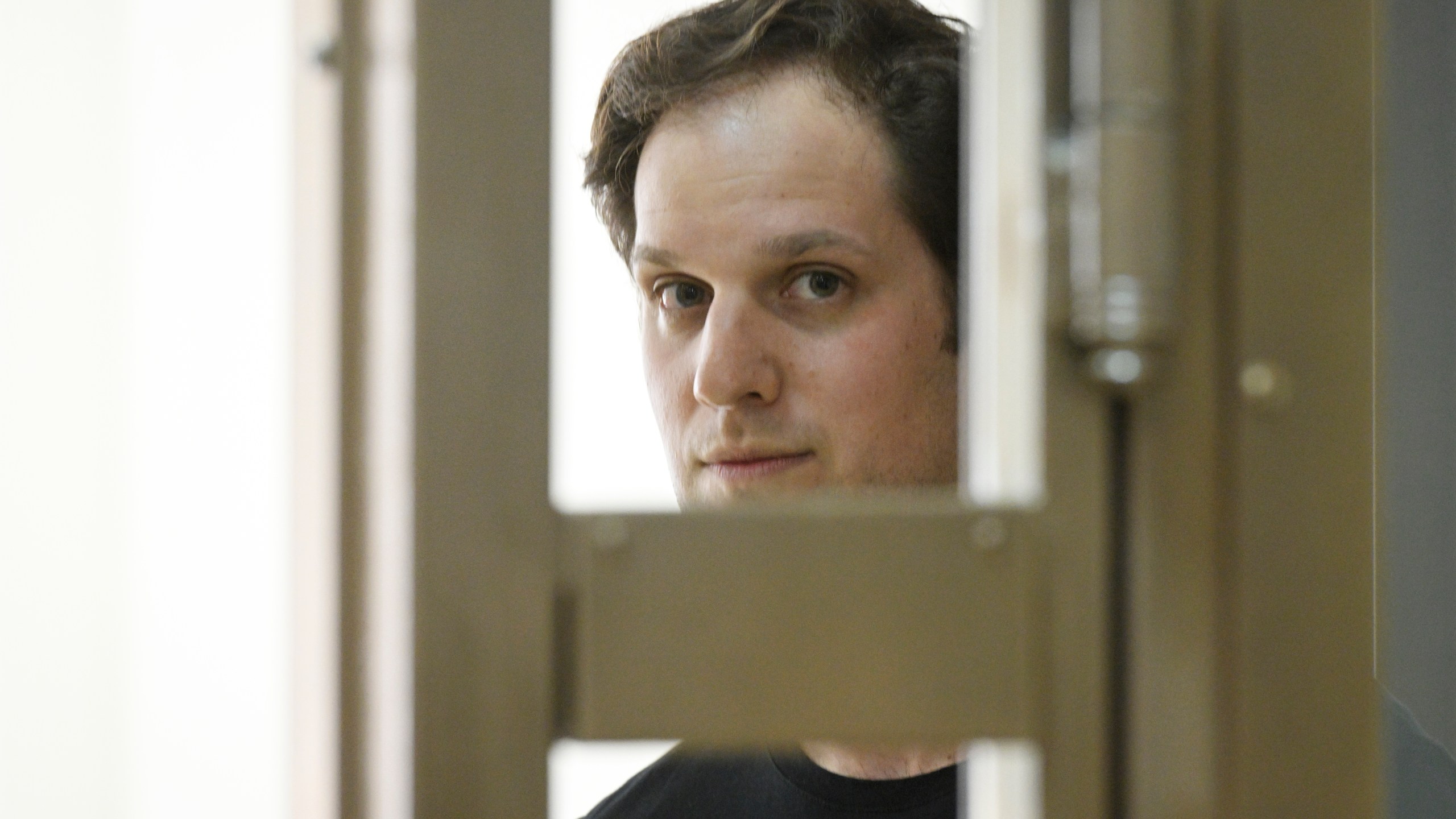 Wall Street Journal reporter Evan Gershkovich stands in a glass cage in a Moscow courtroom.