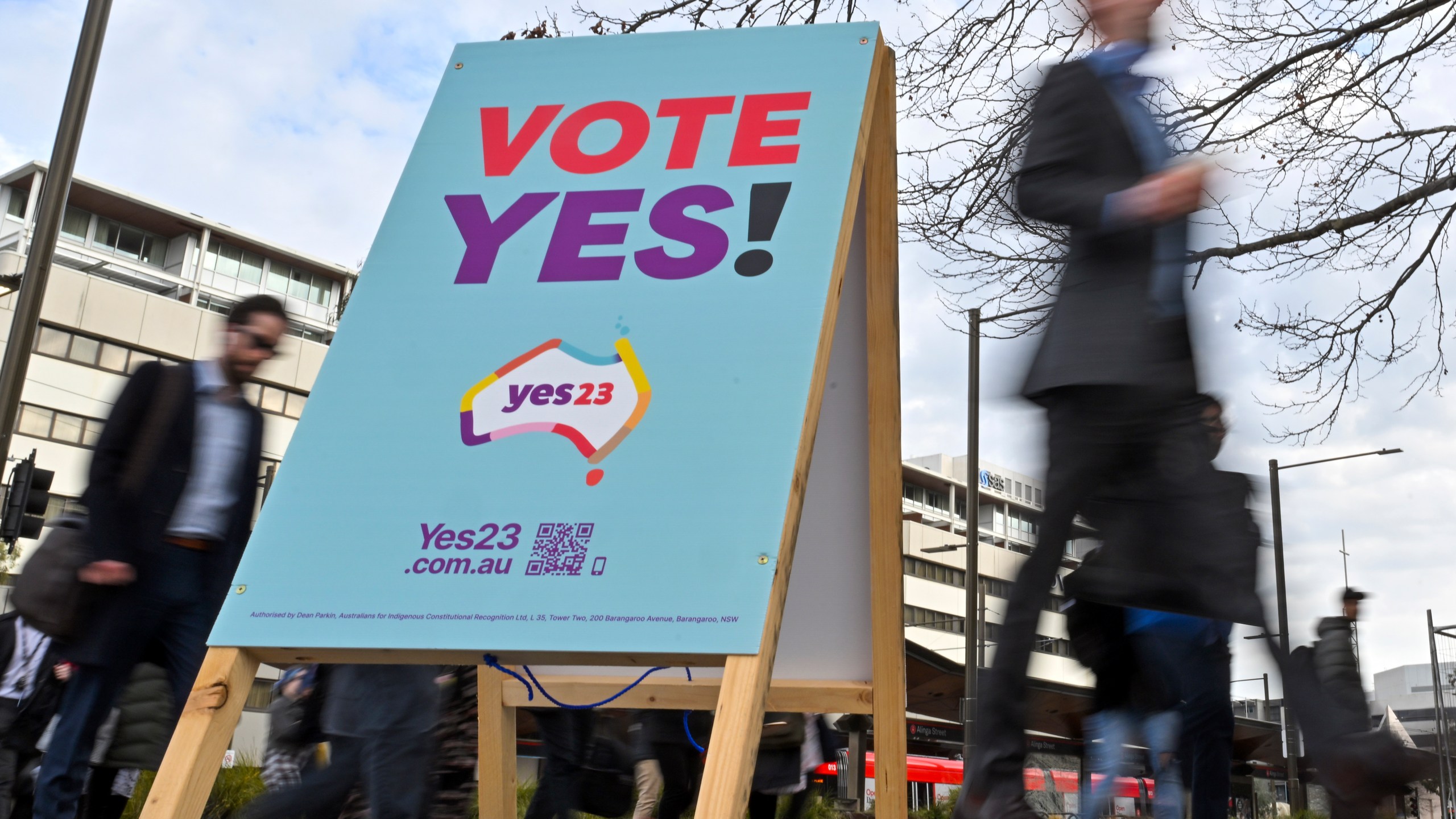 Commuters walk past a vote "yes" stand for the upcoming Voice referendum at the Civic Bus Interchange in Canberra, Australia, Wednesday, Aug. 30, 2023. Prime Minister Anthony Albanese announced that Australians will vote on Oct. 14 in a referendum that would enshrine in the nation's constitution a mechanism for Indigenous people to advise Parliament on policies that effect their lives known as the Voice. (Mick Tsikas/AAP Image via AP)