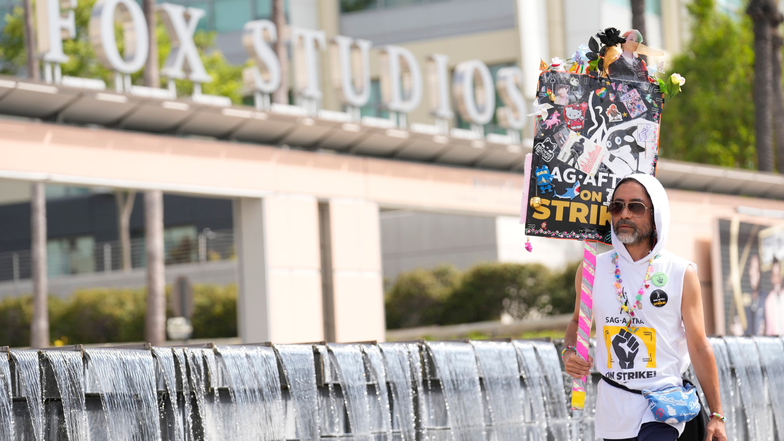 SAG-AFTRA member Newt Kane walks on a picket line outside Fox studios on Monday, Aug. 14, 2023, in Los Angeles. The Hollywood writers strike passed the 100-day mark as the film and television industries remain paralyzed by dual actors and screenwriters strikes. (AP Photo/Chris Pizzello)