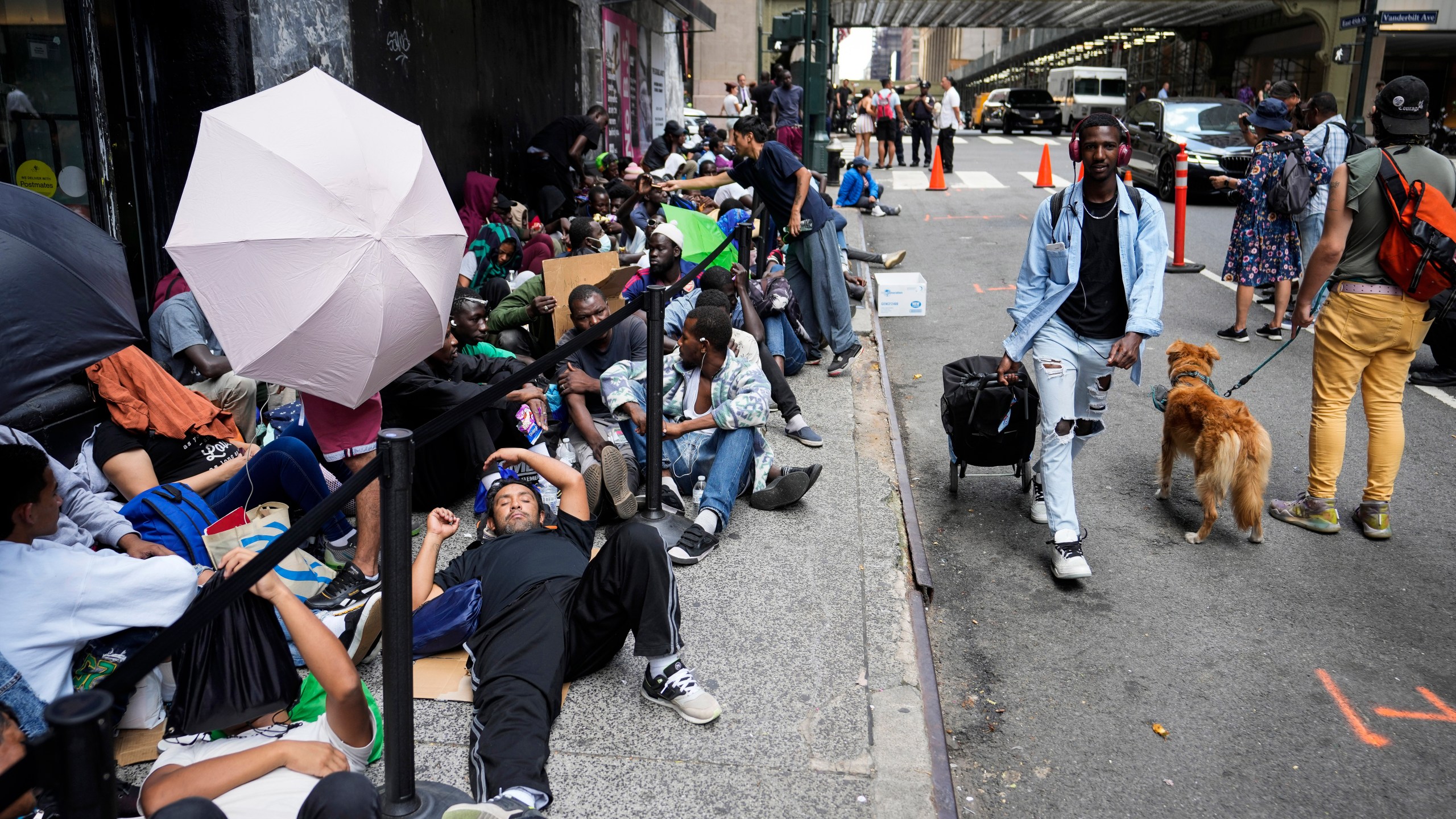 Migrants sit in a queue near temporary housing in New York City.