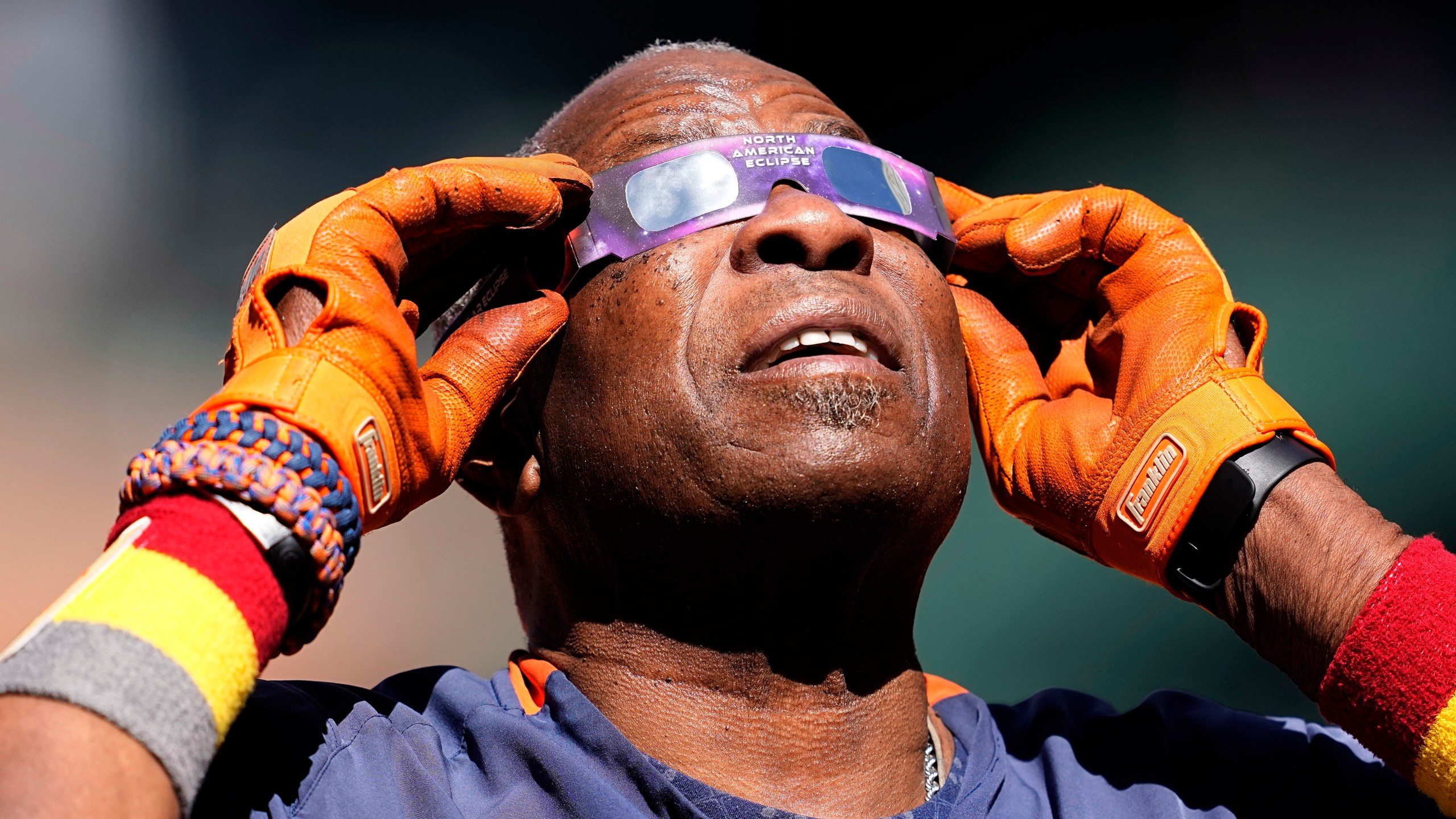 Houston Astros manager Dusty Baker Jr. uses protective glasses to look at the solor eclipse during the team's baseball practice in Houston, Saturday, Oct. 14, 2023. The Astros are scheduled to play the Texas Rangers in Game 1 of baseball's American League Championship Series on Sunday. (AP Photo/Tony Gutierrez)