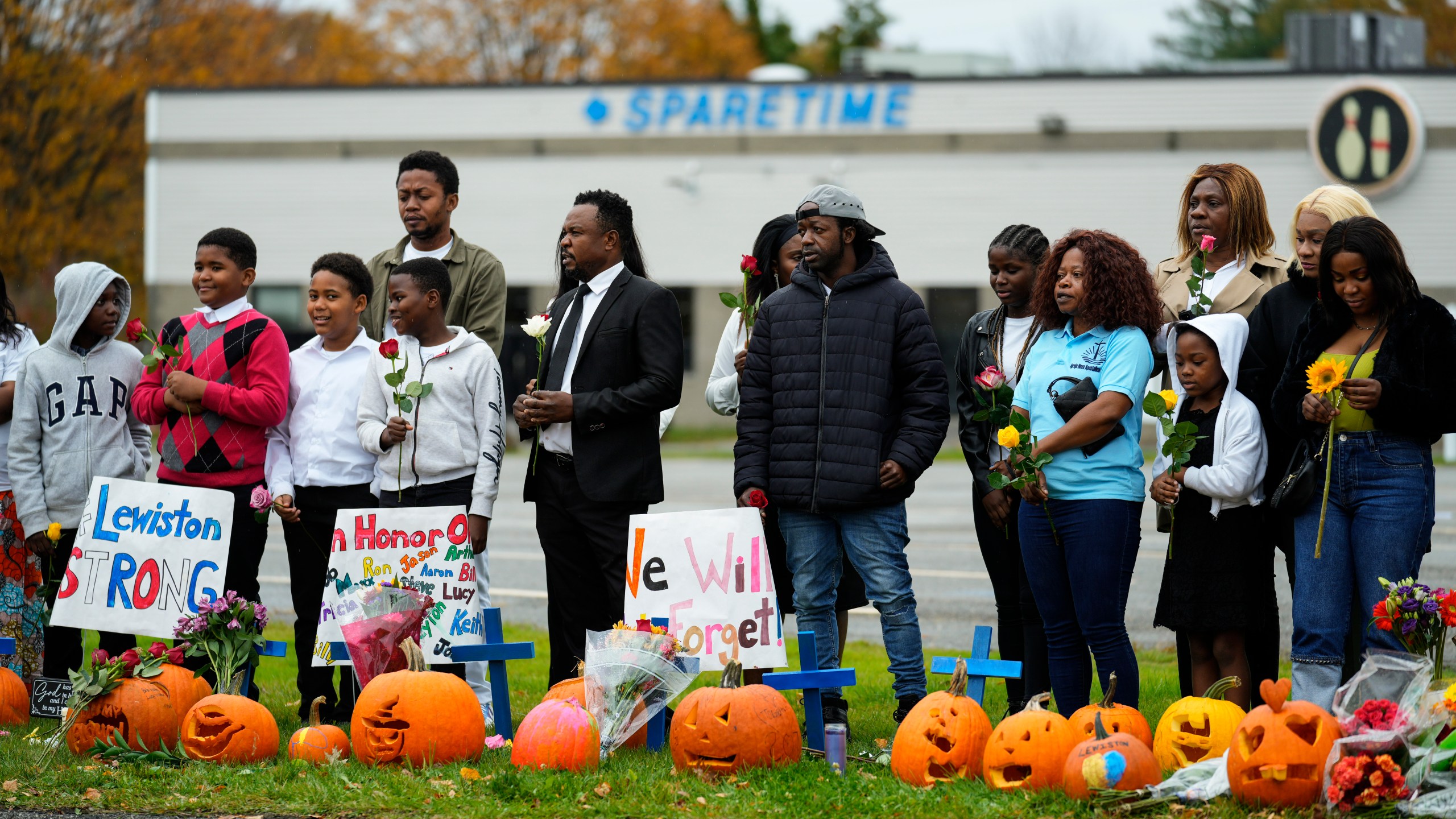 Members of the New Apostolic Church sing and pray at a makeshift memorial outside a bowling alley, the site of one of this week's mass shootings, Sunday, Oct. 29, 2023, in Lewiston, Maine. A gunman killed multiple people at the bowling alley and a bar in Lewiston on Wednesday. (AP Photo/Matt Rourke)