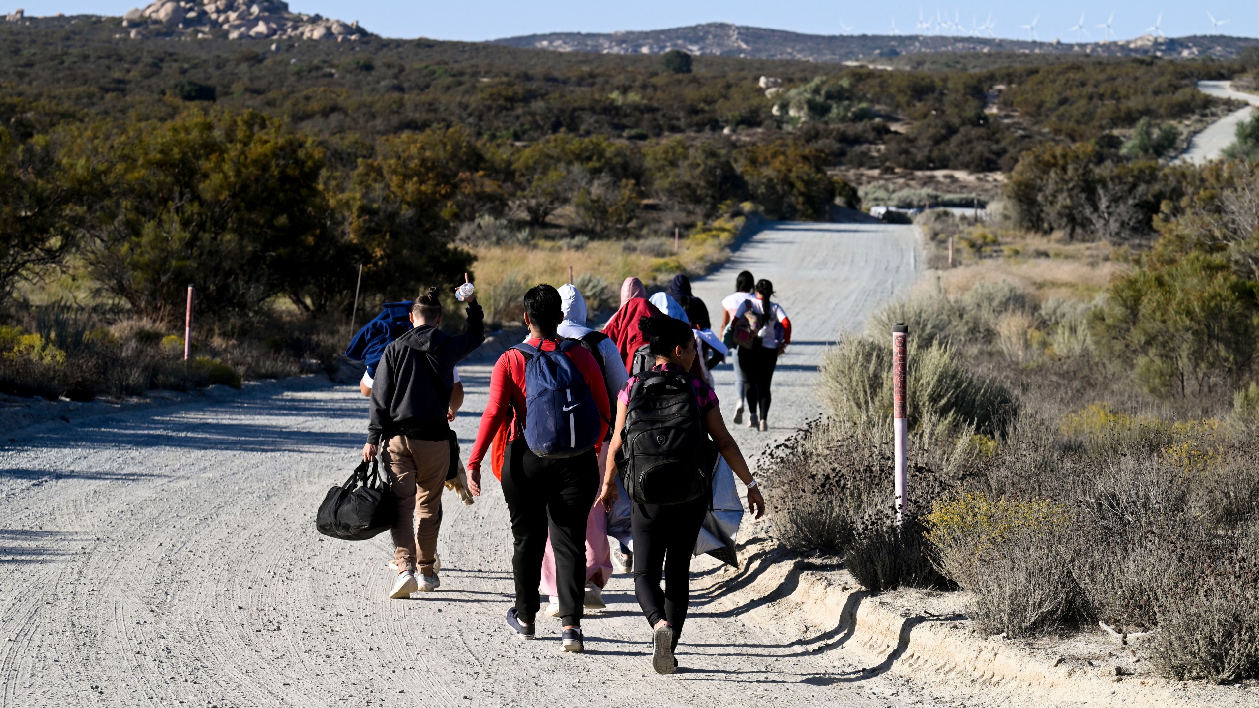 FILE - Asylum-seekers walk to a U.S. Border Patrol van after crossing the nearby border with Mexico, Tuesday Sept. 26, 2023, near Jacumba Hot Springs, Calif. Migrants continue to arrive to desert campsites along California's border with Mexico, as they await processing. Congress is discussing changes to the immigration system in exchange for providing money to Ukraine in its fight against Russia and Israel for the war with Hamas. (AP Photo/Denis Poroy, File)
