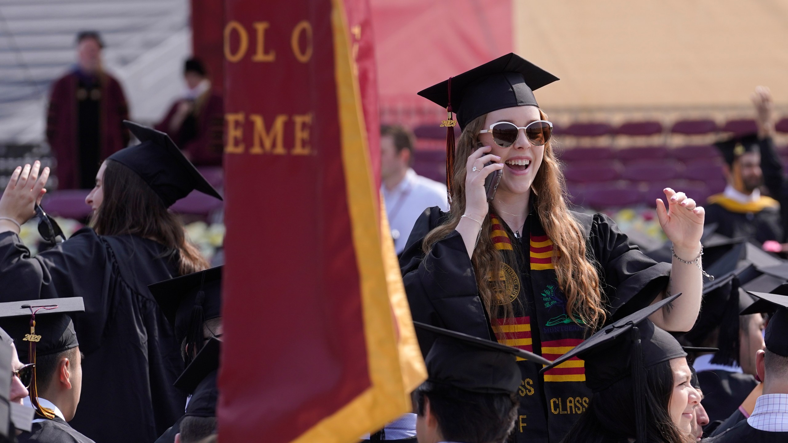 File - A graduating Boston College student speaks on a phone during commencement ceremonies on May 22, 2023, in Boston. The Free Application for Federal Student Aid, or FAFSA, has been available on and off for a few days now. While many have been able to take advantage of the new shorter application, many others have struggled to even open the application. (AP Photo/Steven Senne, File)