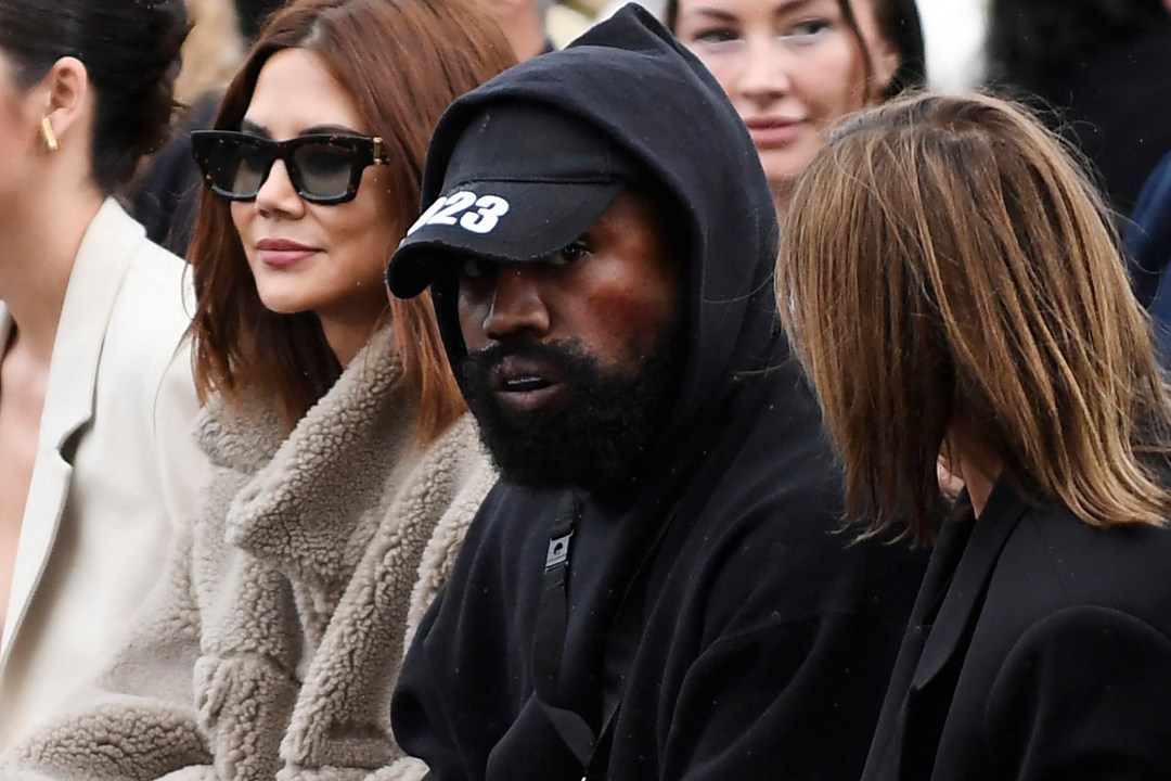 Kanye in a hat and hooded sweater during a fashion show