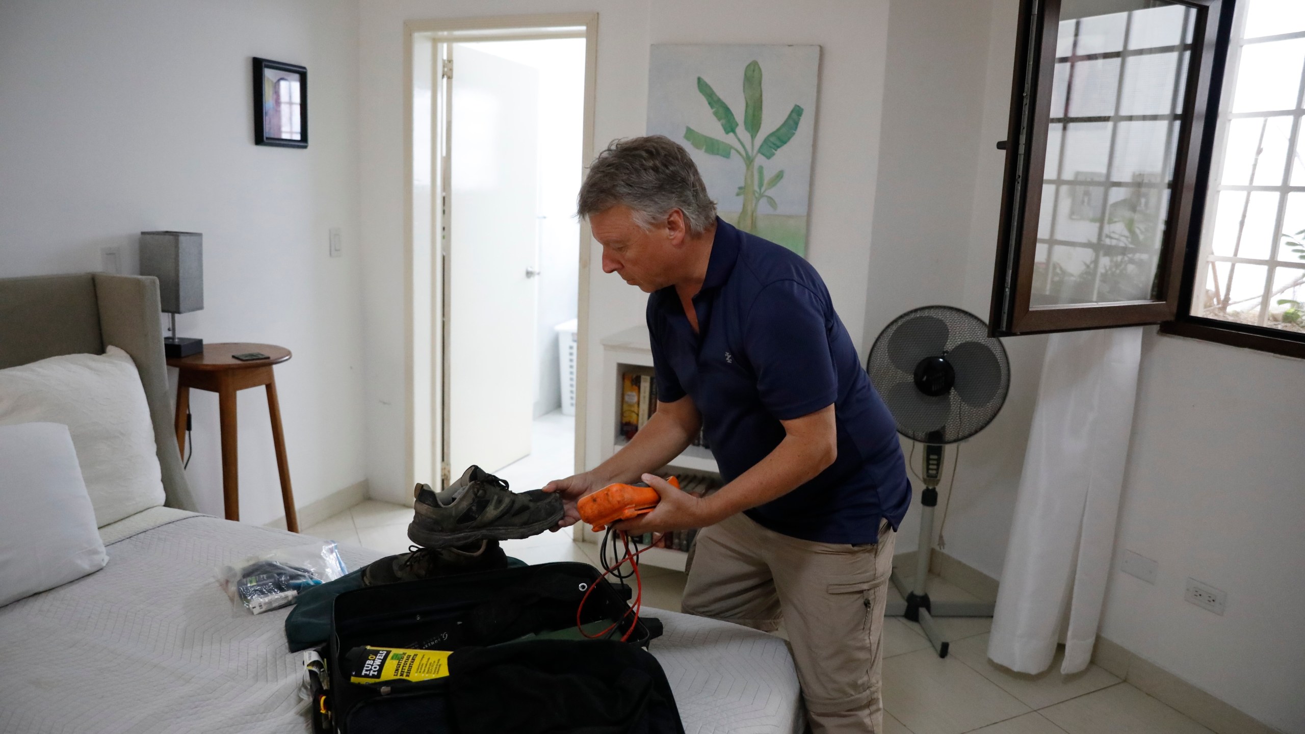 Richard Phillips, a 65-year-old man from the Canadian capital, Ottawa, packs his suitcase in Port-au-Prince, Haiti, Friday, March 8, 2024. Dozens of foreigners, including many from the U.S. and Canada, are stranded in Haiti, desperately trying to leave the violence-torn country where anti-government gangs are battling police and have already shut down both of the country's international airports. (AP Photo/Odelyn Joseph)