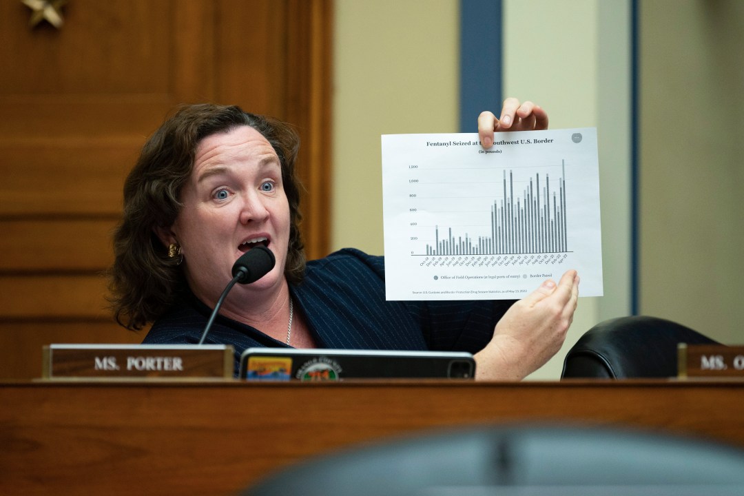 Katie Porter holds up a sheet of paper during a hearing