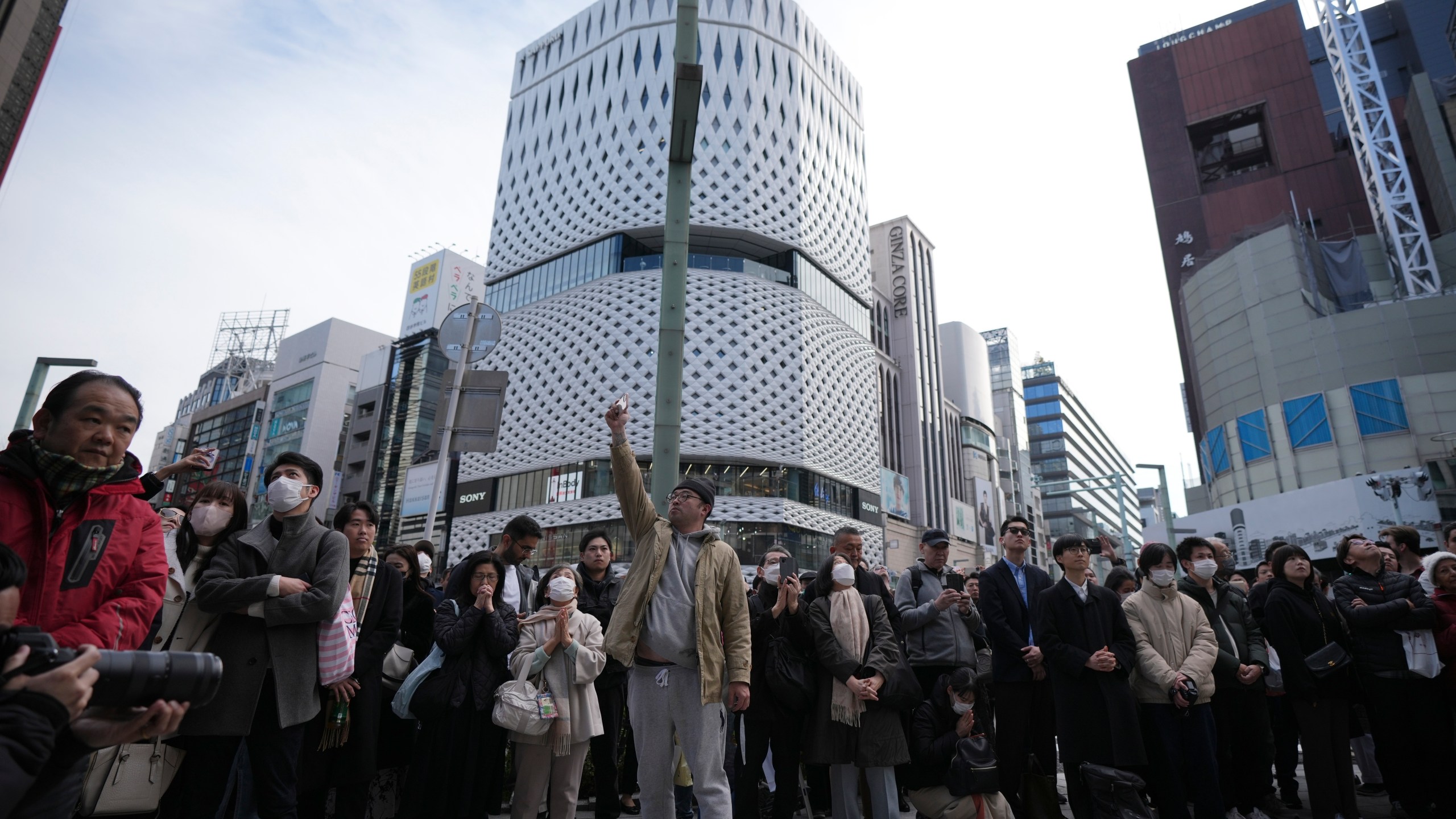 Bystanders gather when an annual tribute started at 2:46 p.m. for the victims of a 2011 disaster Monday, March 11, 2024, in Tokyo. Japan on Monday marked the 13th anniversary of the massive earthquake, tsunami and nuclear disaster that struck Japan's northeastern coast. (AP Photo/Eugene Hoshiko)