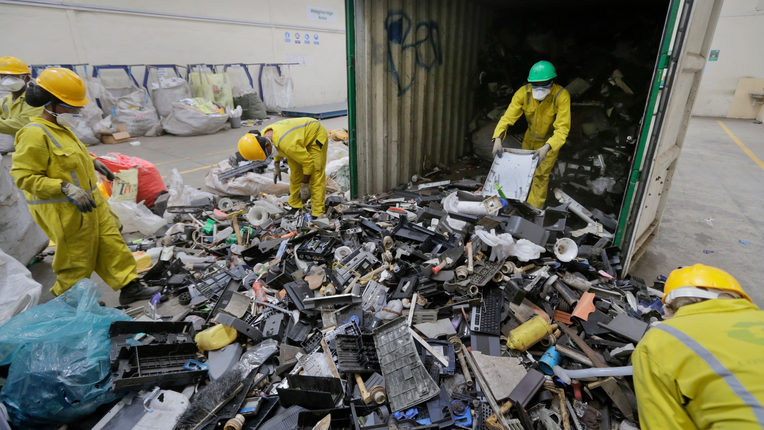 FILE - In this photo taken Monday, Aug. 18, 2014, workers unload and sort through a container full of electronic waste that was collected from a Nairobi slum and brought in for recycling, at the East African Compliant Recycling facility in Machakos, near Nairobi, in Kenya. U.N. agencies warn that electrical waste — everything from discarded refrigerators to TVs to e-scooters to mobile phones — is piling up worldwide, and recycling rates are low and likely to fall even further. (AP Photo/Ben Curtis, File)