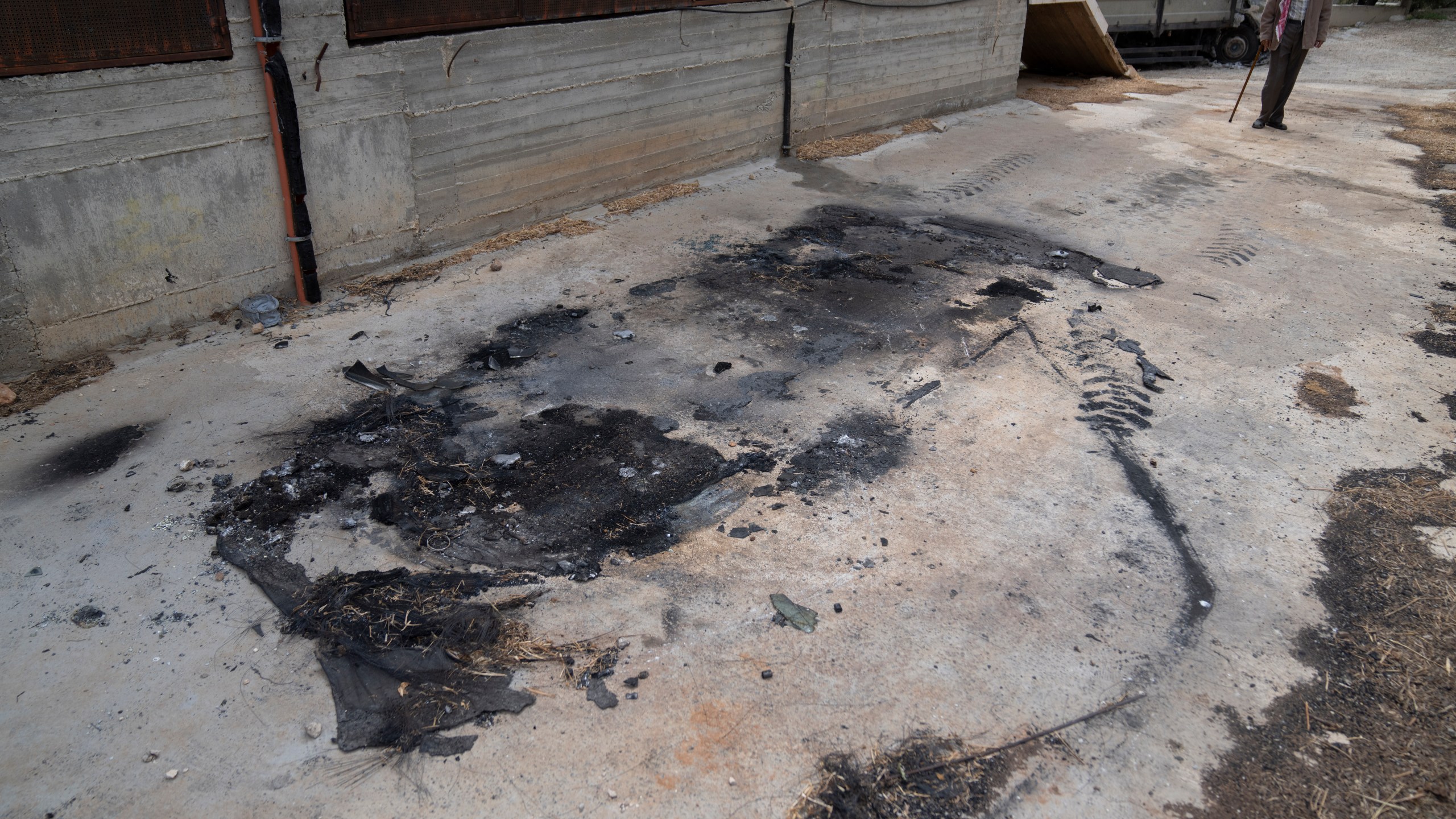 Fathi Dawabsha, 82, walks toward the remains of a family vehicle that was torched during an attack by Israel settlers last month, in the West Bank village of Duma, Tuesday, April 30, 2024. (AP Photo/Nasser Nasser)
