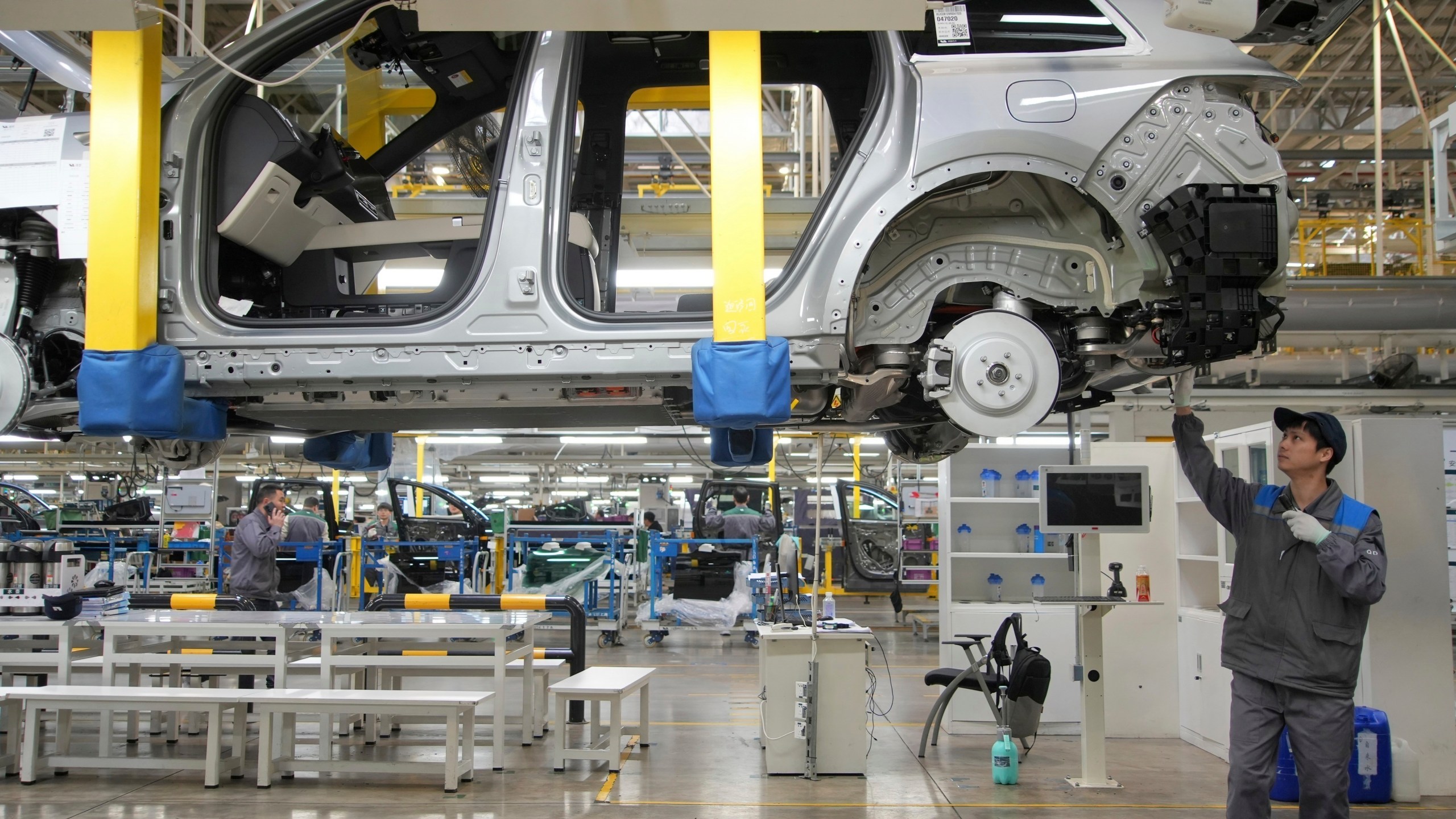 A worker assembles an SUV in a factory