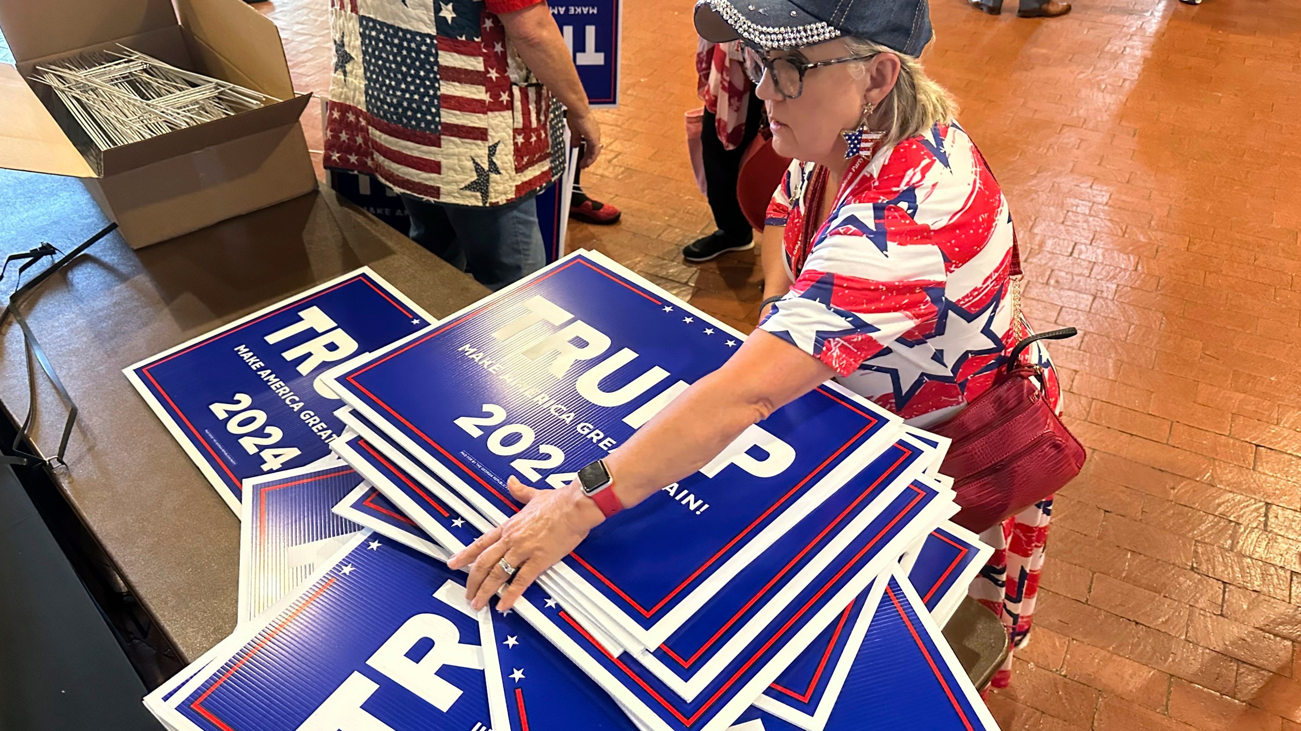Ginger Hurmence of Lincolnton, Ga., picks up Republican presidential candidate Donald Trump yard signs at the Georgia Republican Party State Convention in Columbus, Ga., on Saturday, May 18, 2024. (AP Photo/Jeff Amy)