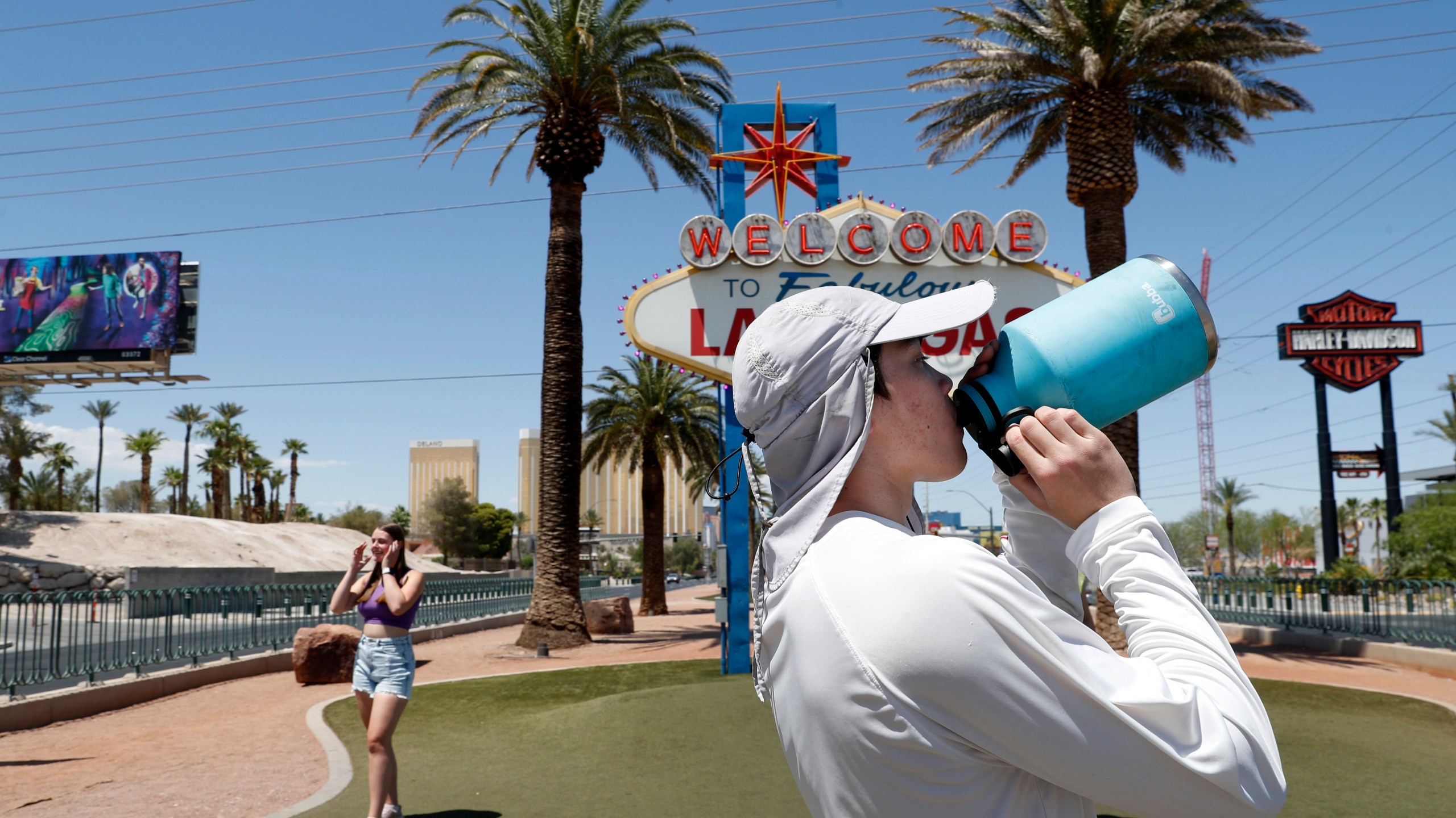 Dean Leano takes a water break while photographing tourists at the Welcome to Fabulous Las Vegas sign in Las Vegas Thursday, June 6, 2024. (Steve Marcus/Las Vegas Sun via AP)