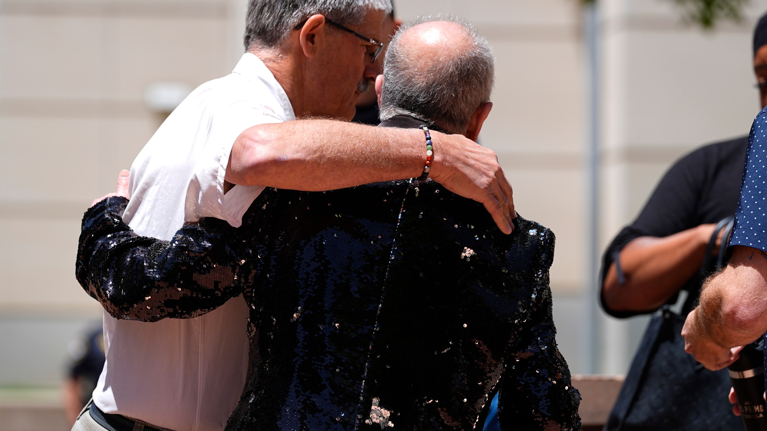 Ed Sanders, right, is hugged after speaking to reporters following the sentencing of Anderson Lee Aldrich, the shooter who killed five people and injured 19 others at an Colorado Springs, Colo., LGBTQ+ club, at a hearing in federal court Tuesday, June 18, 2024, in Denver. (AP Photo/David Zalubowski)