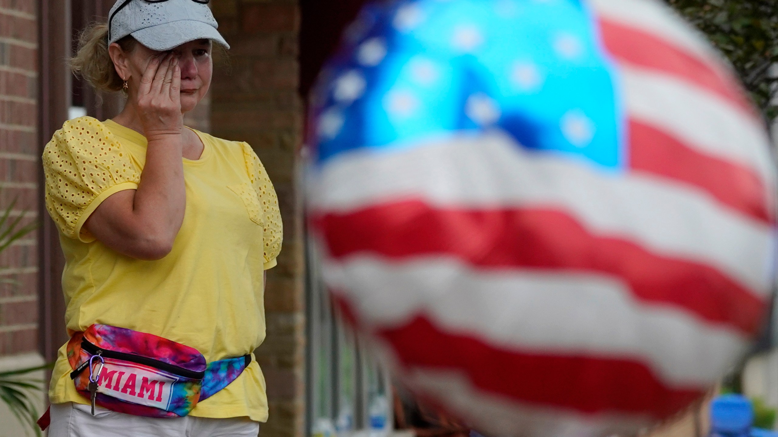 FILE - A woman wipes away tears after a mass shooting at an Independence Day parade that left seven people dead and dozens wounded, in the Chicago suburb Highland Park, July 4, 2022. Violence and mass shootings often surge in the summer months, especially around the Fourth of July, historically one of the deadliest days each year. (AP Photo/Nam Y. Huh, File)