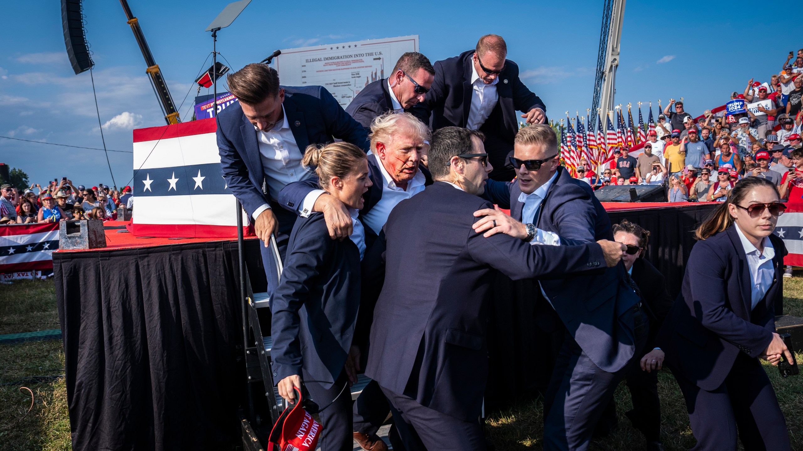 Secret Service agents rush Donald Trump offstage.