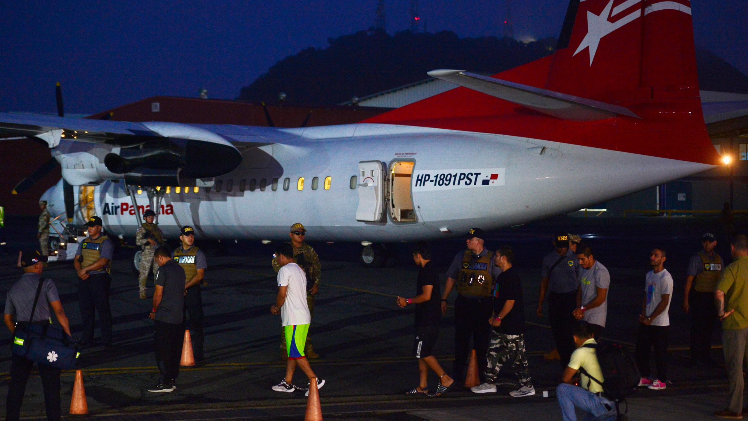 Colombian migrants walk in handcuffs and shackles to a plane for deportation at Marcos A. Gelabert de Albrook Airport in Panama City, Tuesday, Aug. 20, 2024. (AP Photo/Agustin Herrera)