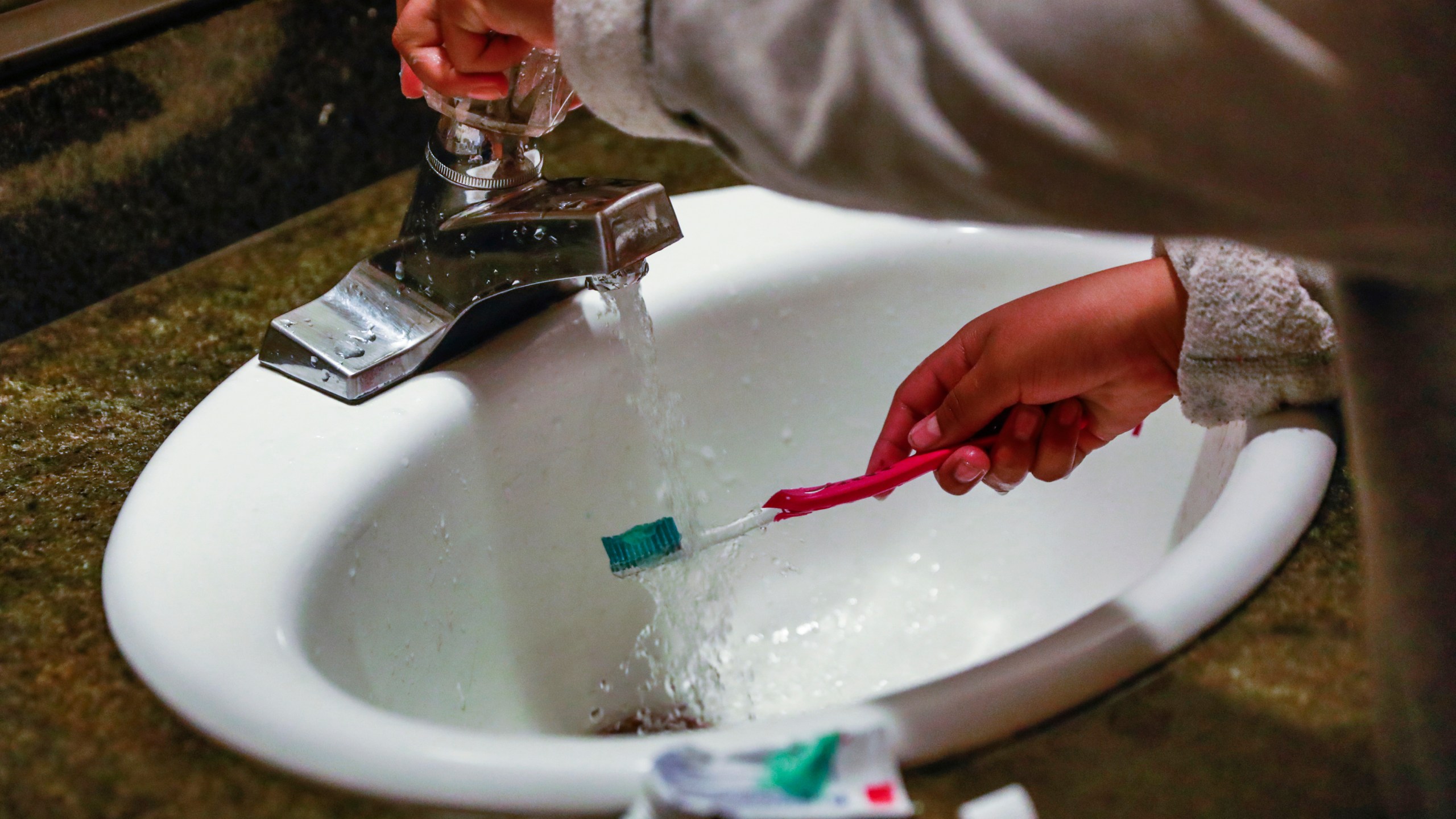A child rinses a toothbrush in San Francisco on June 18, 2019.