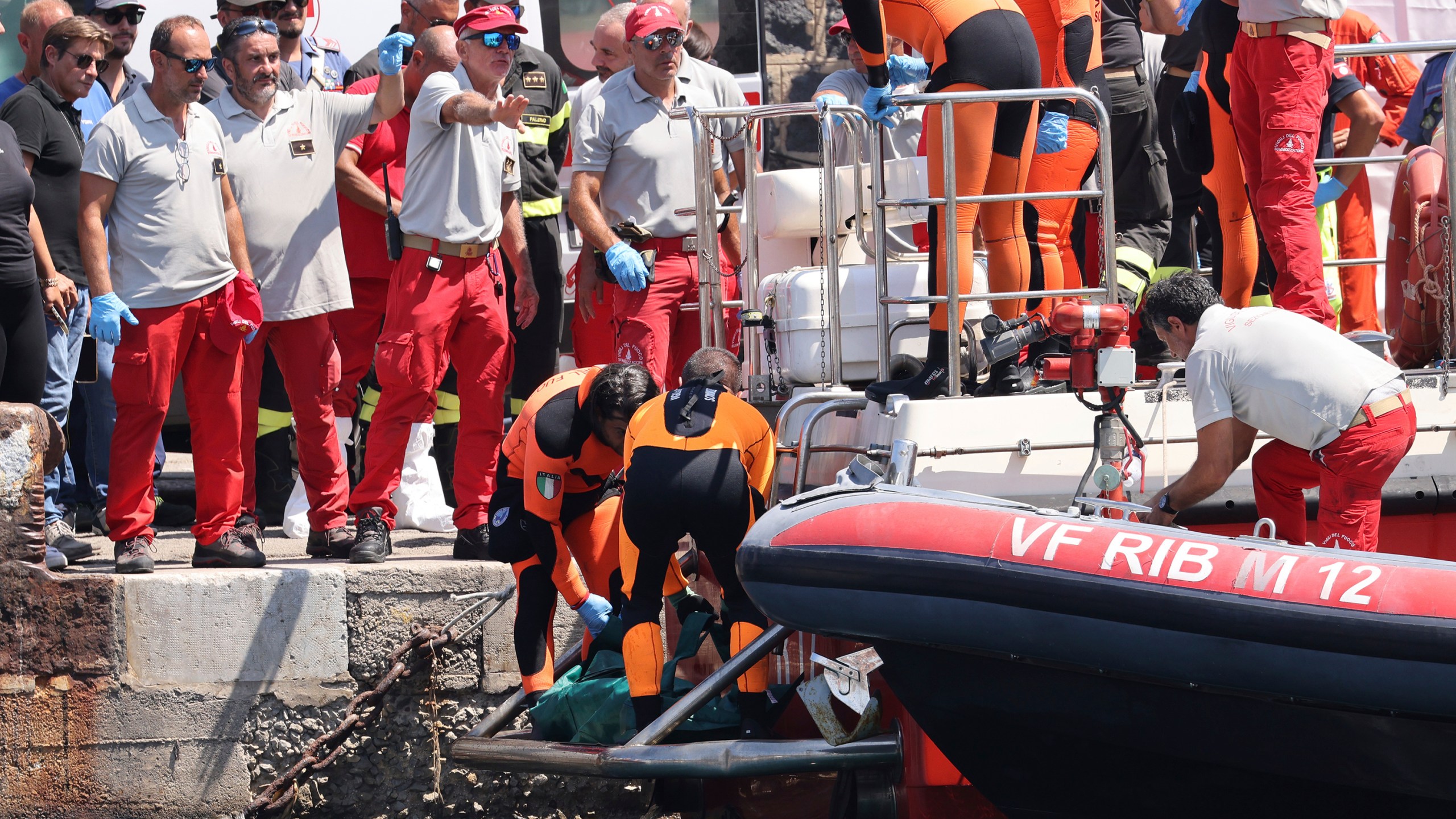 Italian firefighter divers bring ashore in a plastic bag the body of one of the victims of a shipwreck, in Porticello, Sicily, southern Italy, Friday Aug. 23, 2024. Italian rescuers brought ashore the body of the final missing person who was on a superyacht that sunk off the coast of Sicily. (Alberto Lo Bianco/LaPresse via AP)
