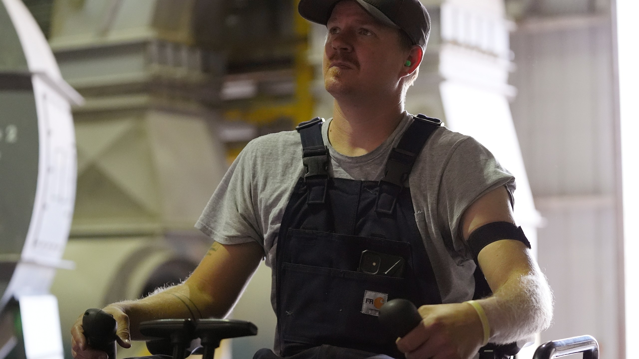 Wyatt Fischer, a furnace mason employee at Cardinal Glass, sits on an excavator while wearing a SlateSafety armband, Thursday, Aug. 22, 2024, in Menomonie, Wis. (AP Photo/Abbie Parr)