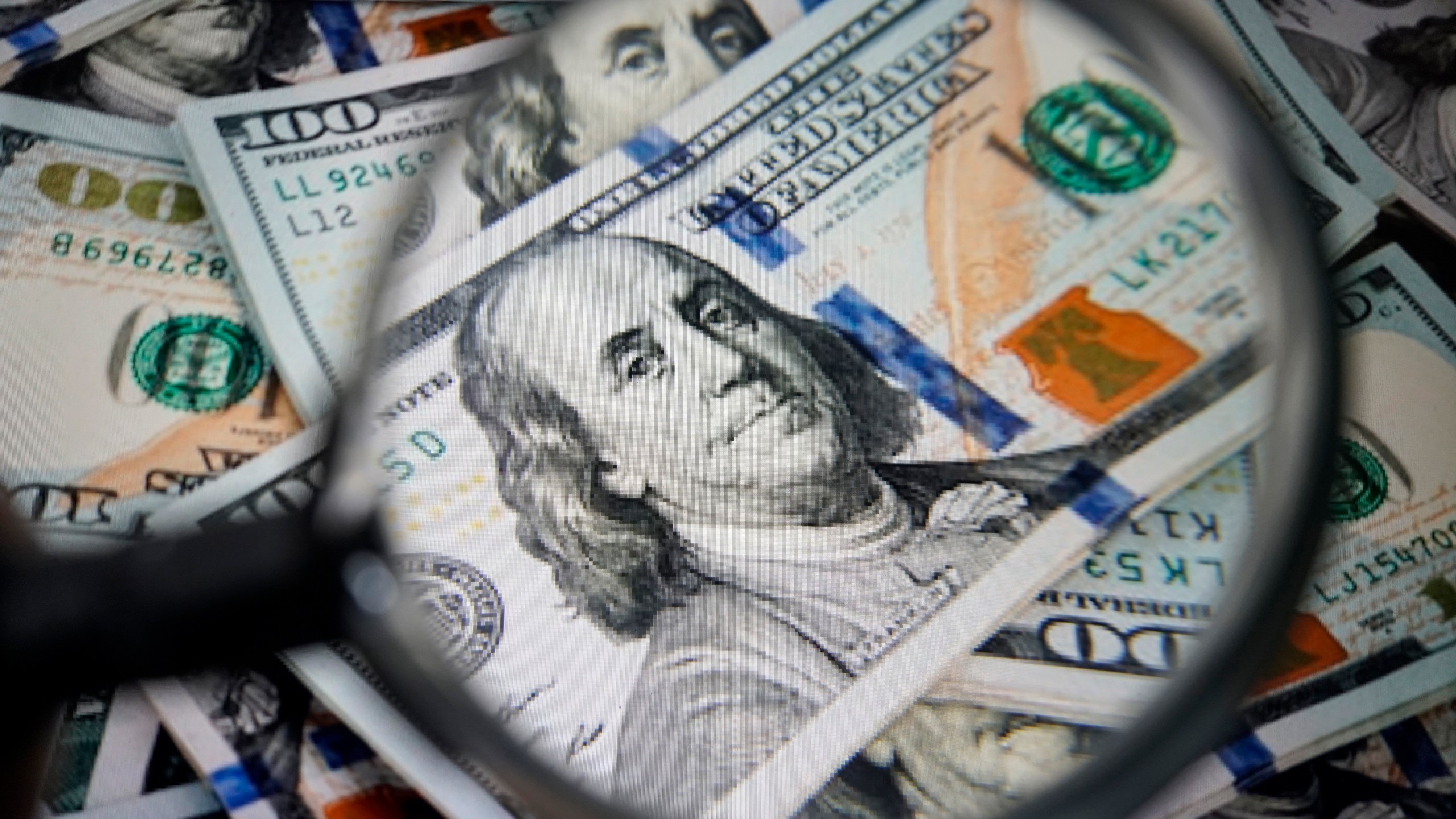 $100 bills under a magnifying glass