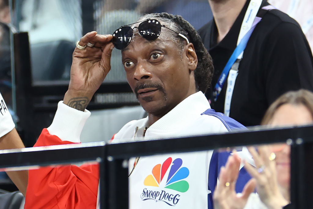 Snoop Dogg sits in the stands at the Olympics