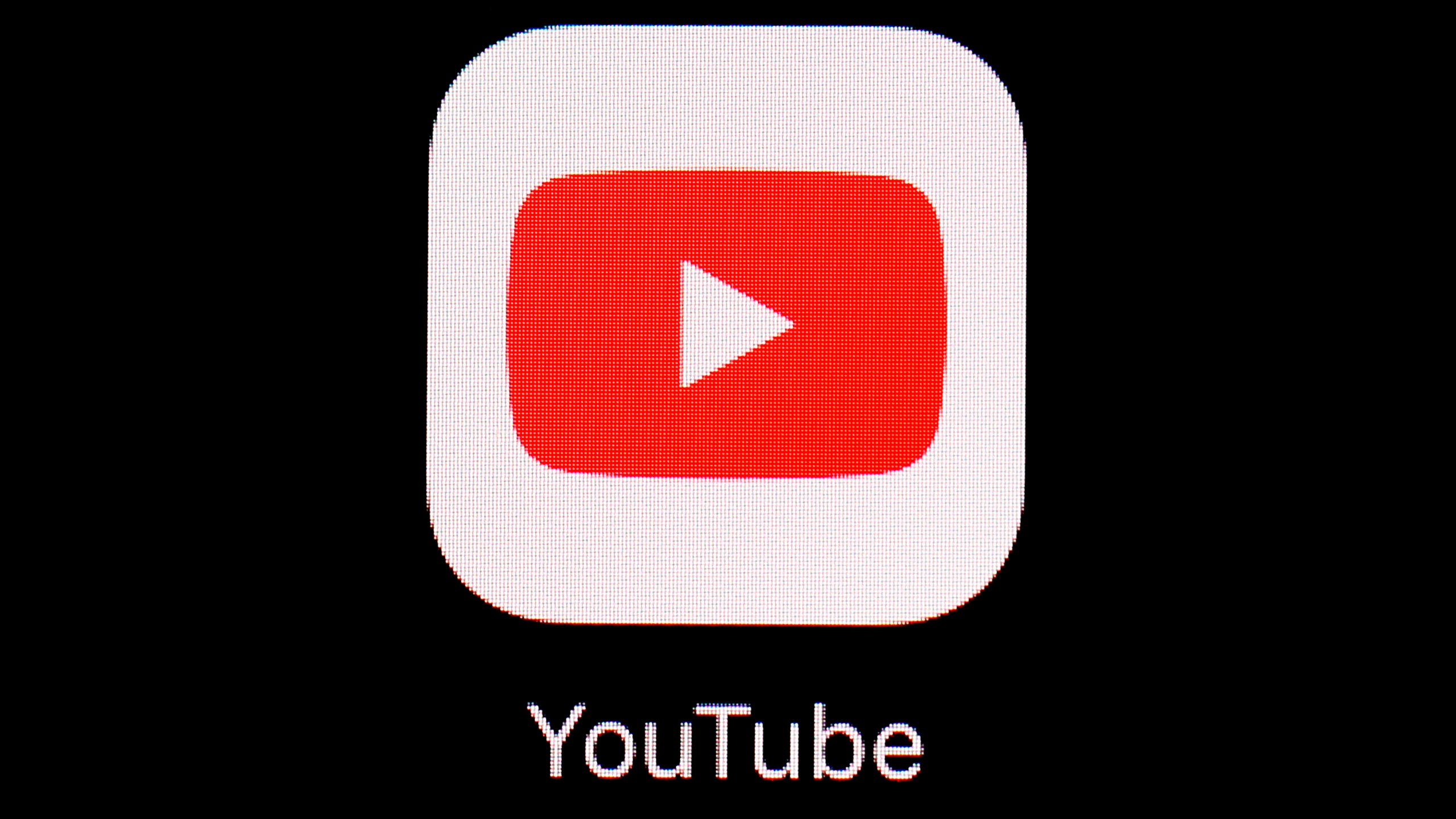 The YouTube logo, a red rectangle and white play button in the center of it sits on a black background on an iPad