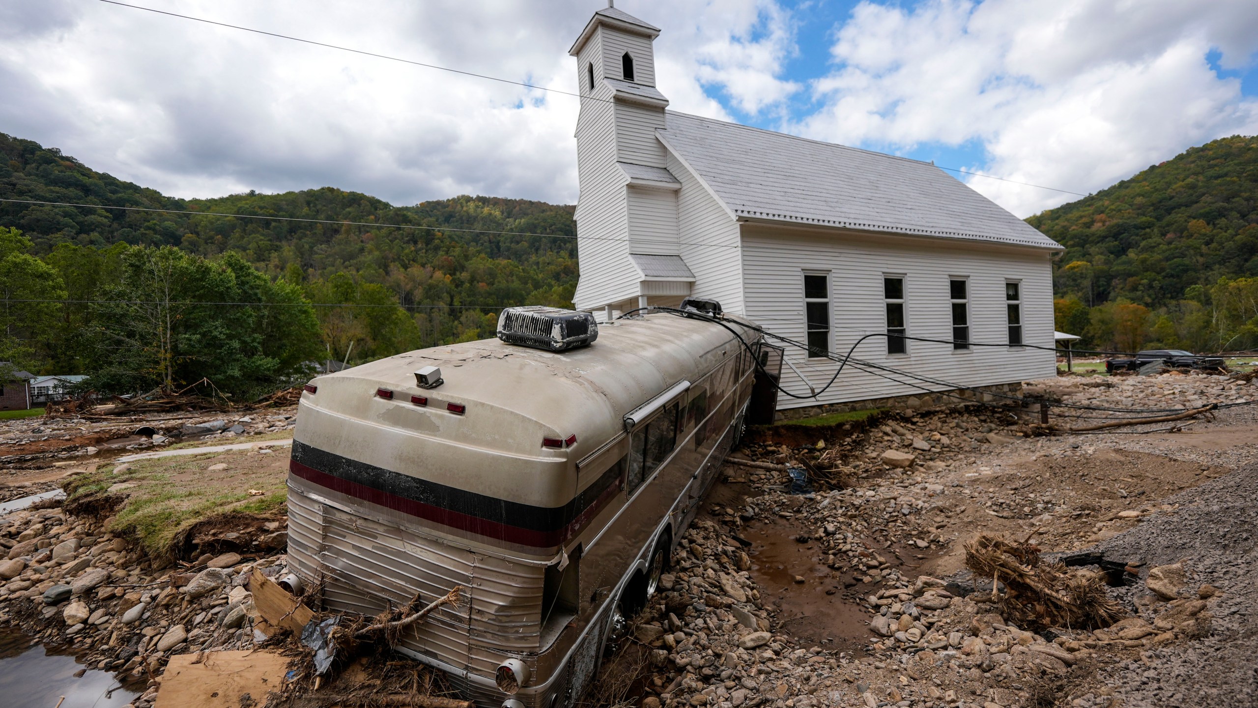 A bus pushed by flood waters rests against Laurel Branch Baptist church in the aftermath of Hurricane Helene, Thursday, Oct. 3, 2024, in Pensacola, N.C. (AP Photo/Mike Stewart)
