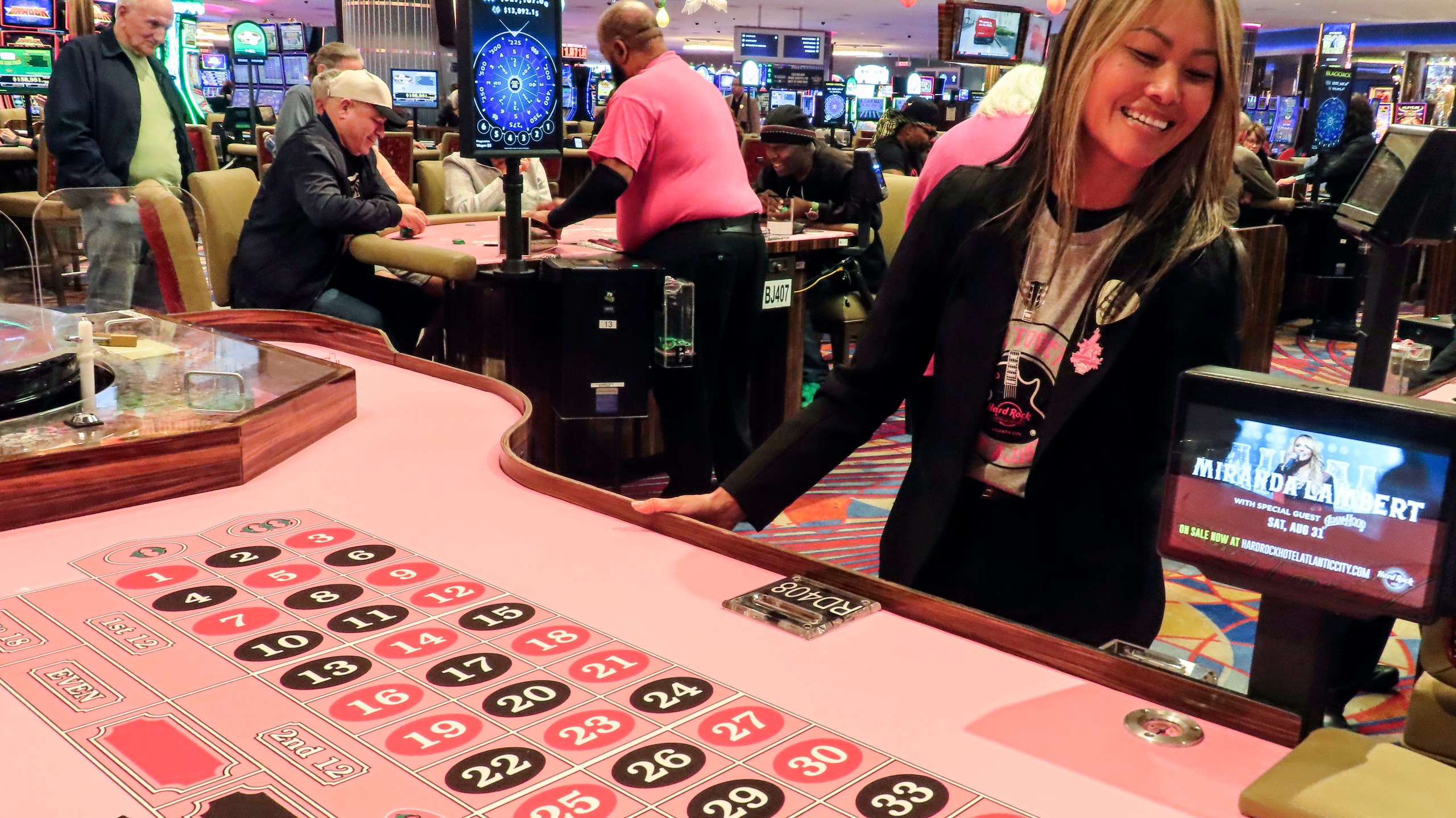 Lee Johnson, a games manager at the Hard Rock casino, checks a roulette table covered in pink felt for breast cancer awareness month before it opens for use in Atlantic City, N.J., Thursday, Oct. 3, 2024. (AP Photo/Wayne Parry)