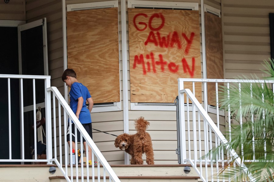 Noah Weibel and his dog Cookie climb the steps to their home as their family prepares for Hurricane Milton on Monday, Oct. 7, 2024, in Port Richey, Fla.
