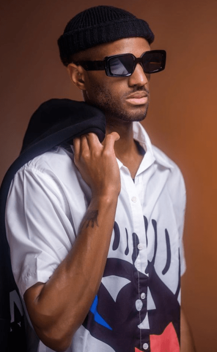 A  black man with sunglasses and a white shirt.