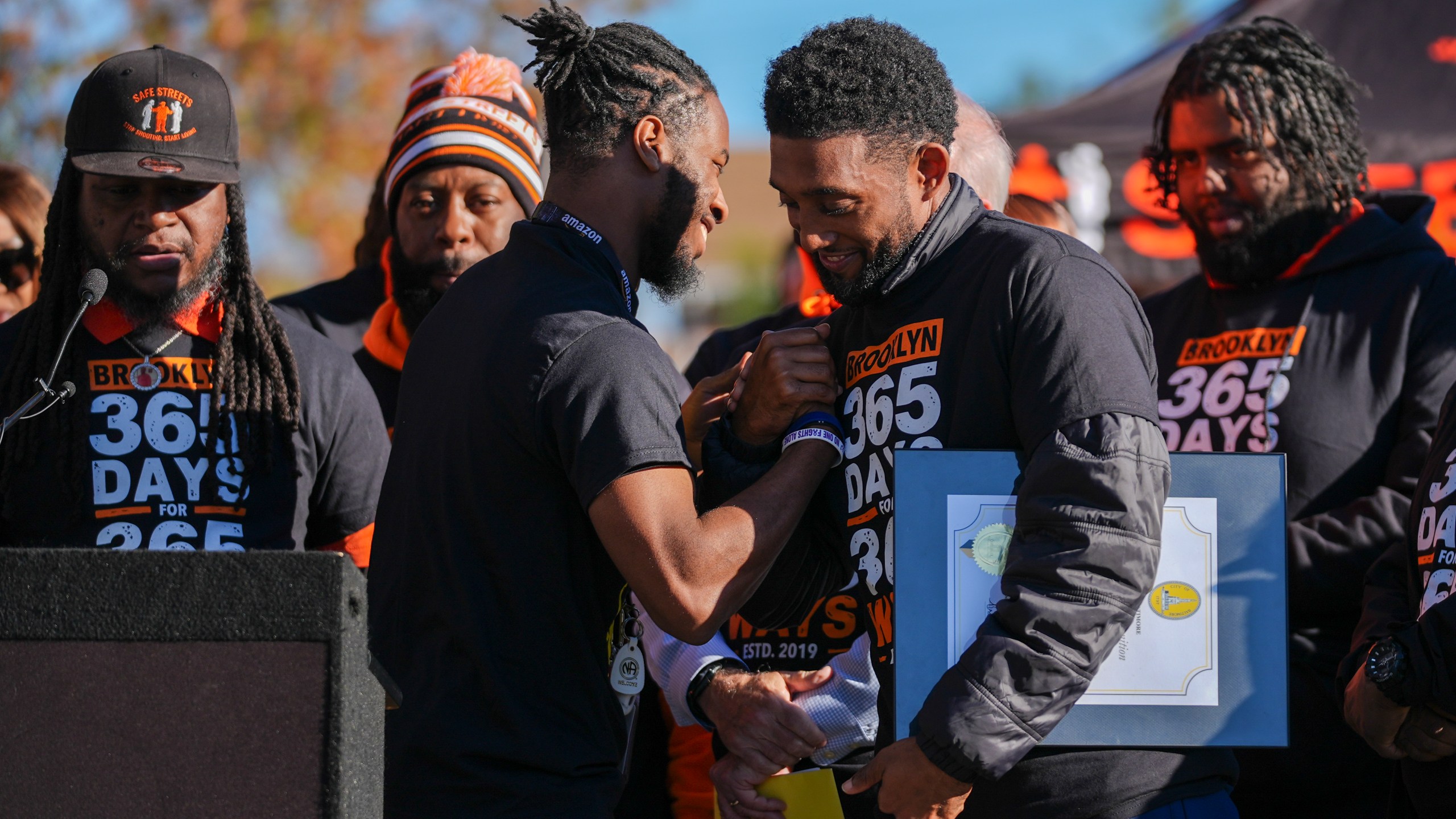 Baltimore Mayor Brandon Scott, right, embraces Adanus Sprillium during a press conference to celebrate achieving over 365 days without a homicide within the Brooklyn neighborhood Safe Streets catchment zone, Tuesday, Nov. 12, 2024, in Baltimore. (AP Photo/Stephanie Scarbrough)