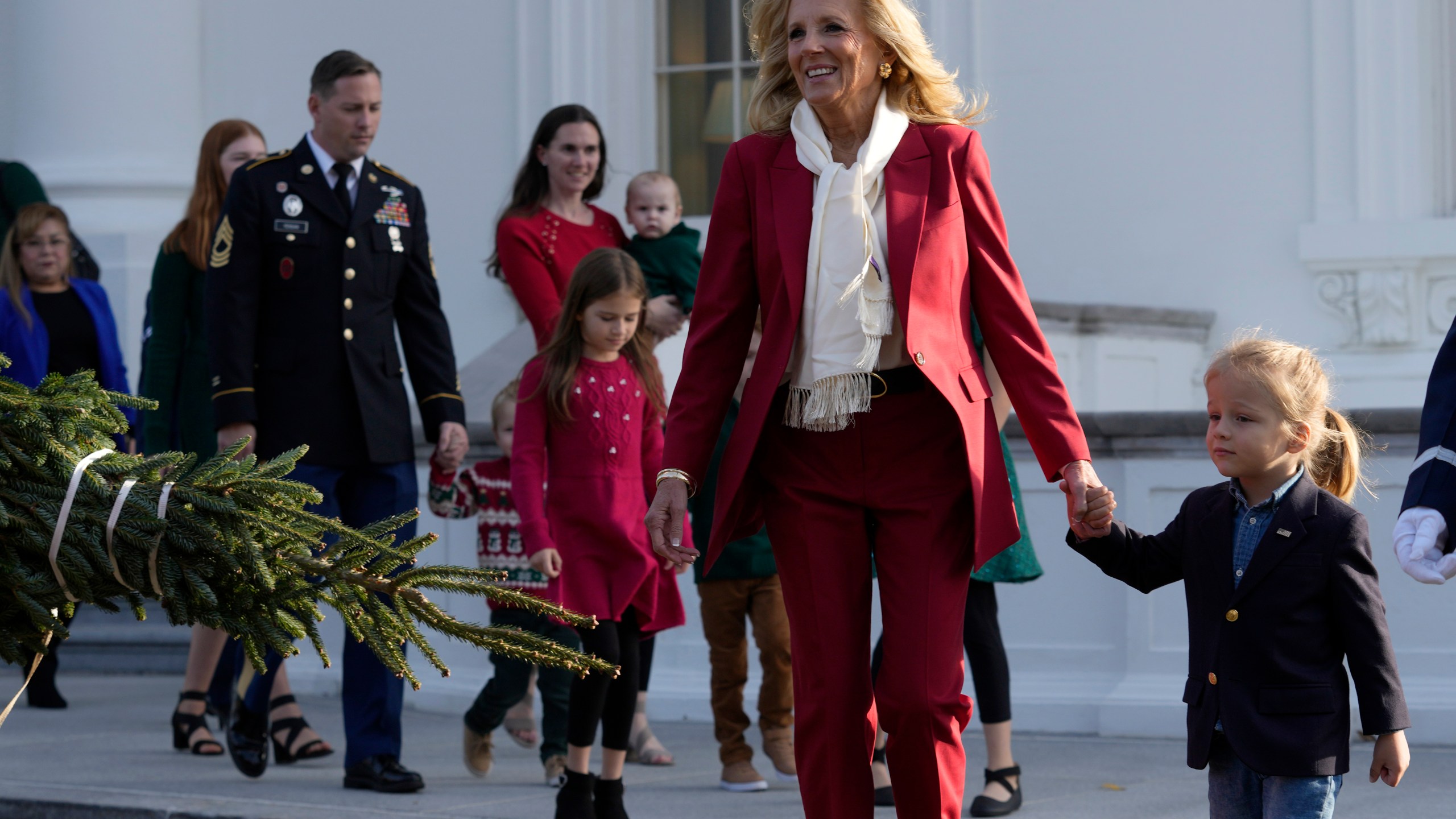 First lady Jill Biden, second right, walks with her grandson Beau Biden, right, to receive the official 2024 White House Christmas Tree on the North Portico of the White House in Washington, Monday, Nov. 25, 2024. Cartner's Christmas Tree Farm from Newland, N.C., provided the Fraser fir that will be displayed in the Blue Room of the White House. (AP Photo/Susan Walsh)
