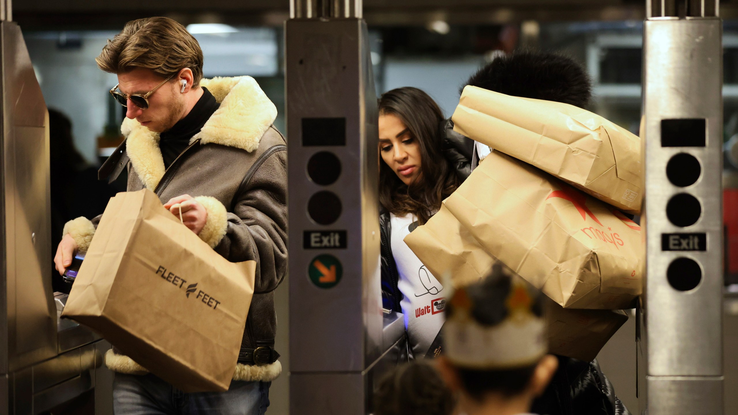 Shoppers manage their bags as they enter a Subway turnstile, Friday, Nov. 29, 2024, in New York. (AP Photo/Heather Khalifa)