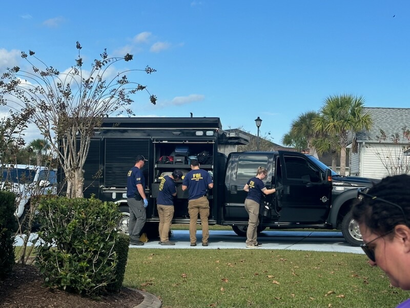 FBI agents looking in a vehicle.