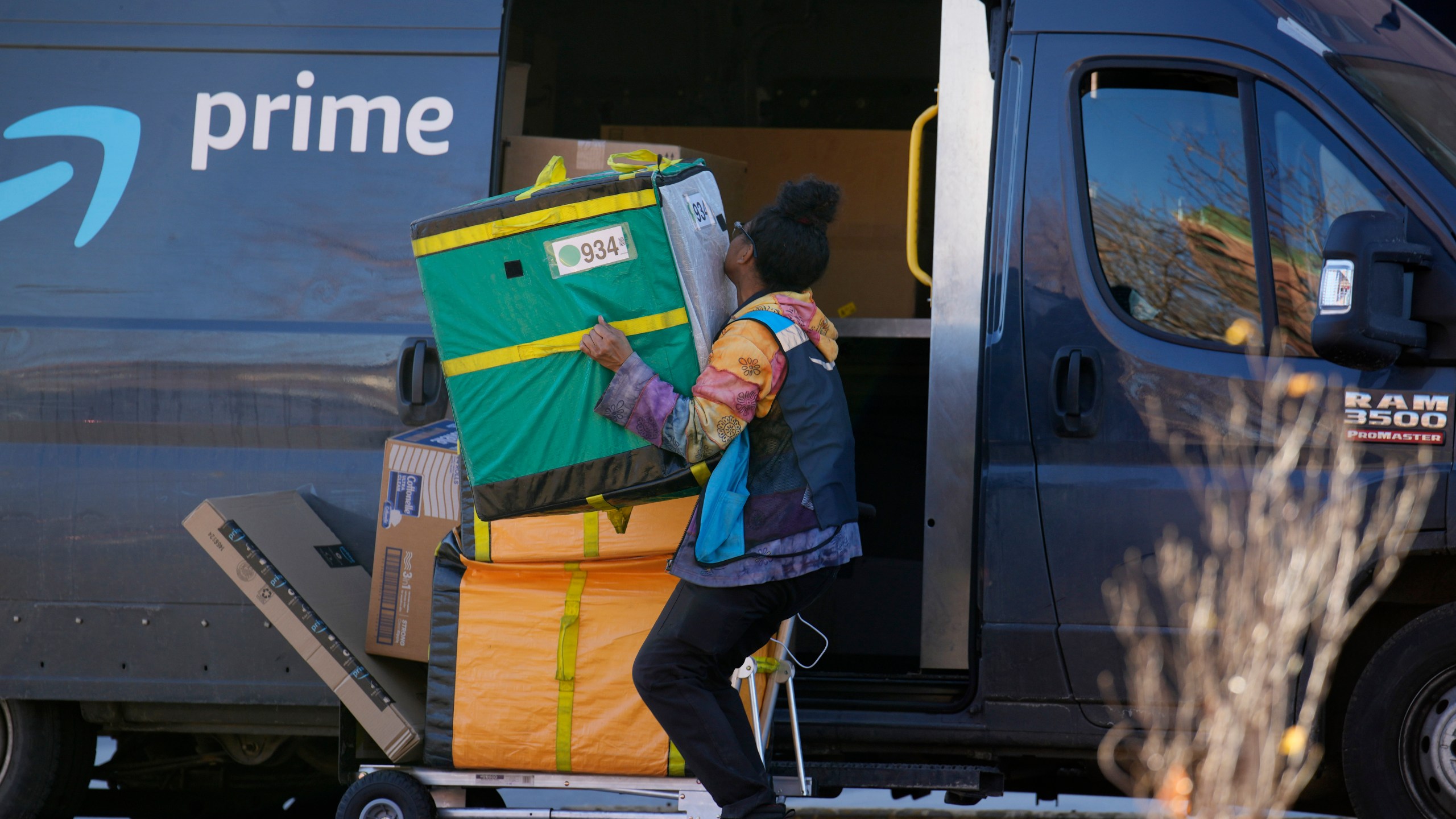 FILE - An Amazon Prime delivery person lifts packages while making a stop on Nov. 28, 2023, in Denver. (AP Photo/David Zalubowski, File)