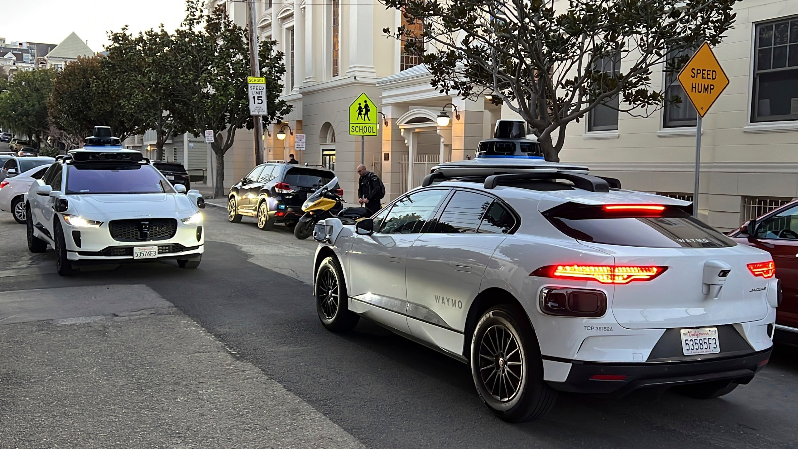 Two Waymo driverless taxis passing one another on a street