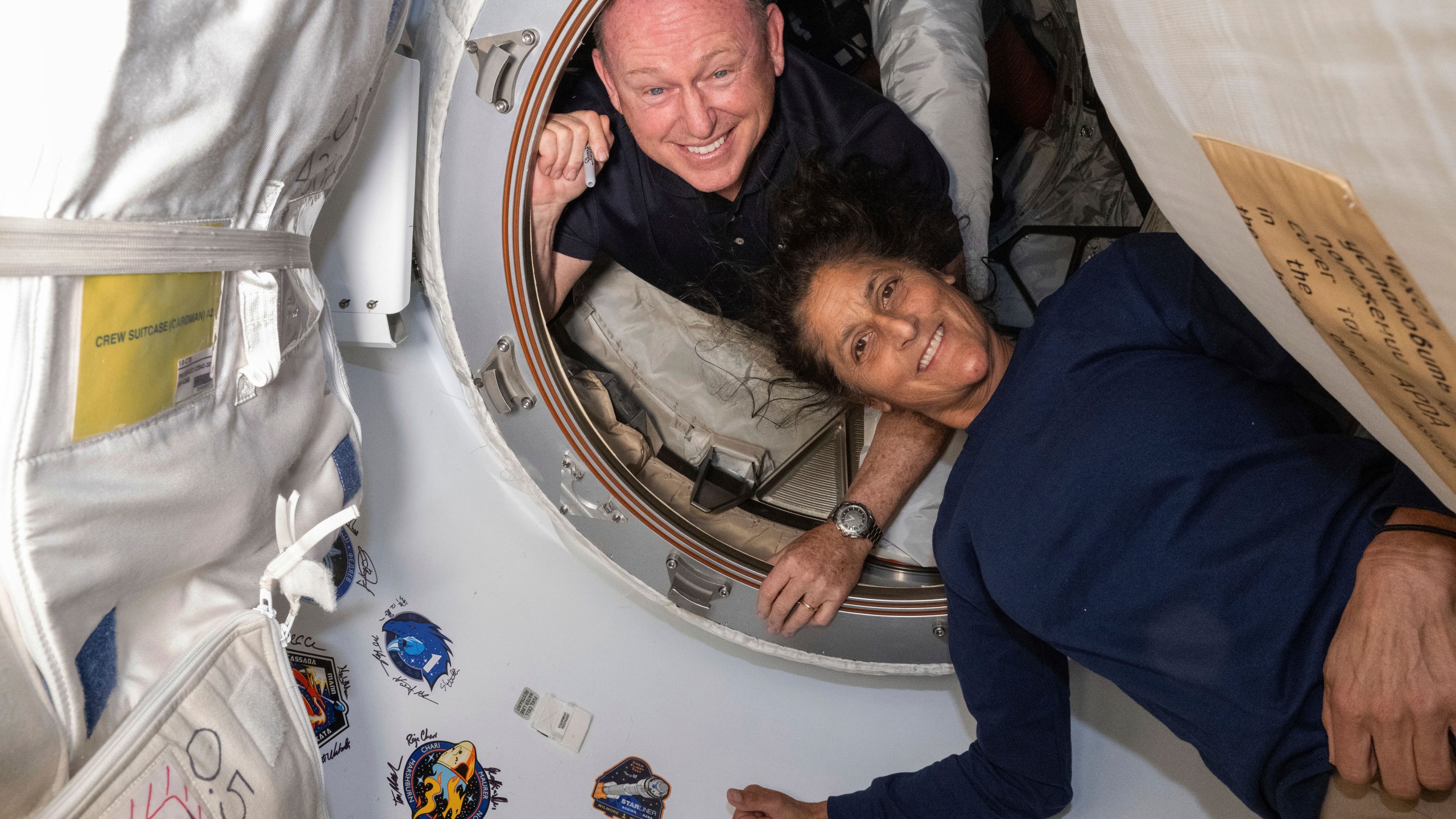 Astronauts Butch Wilmore and Suni Williams pose for a portrait inside a spacecraft.